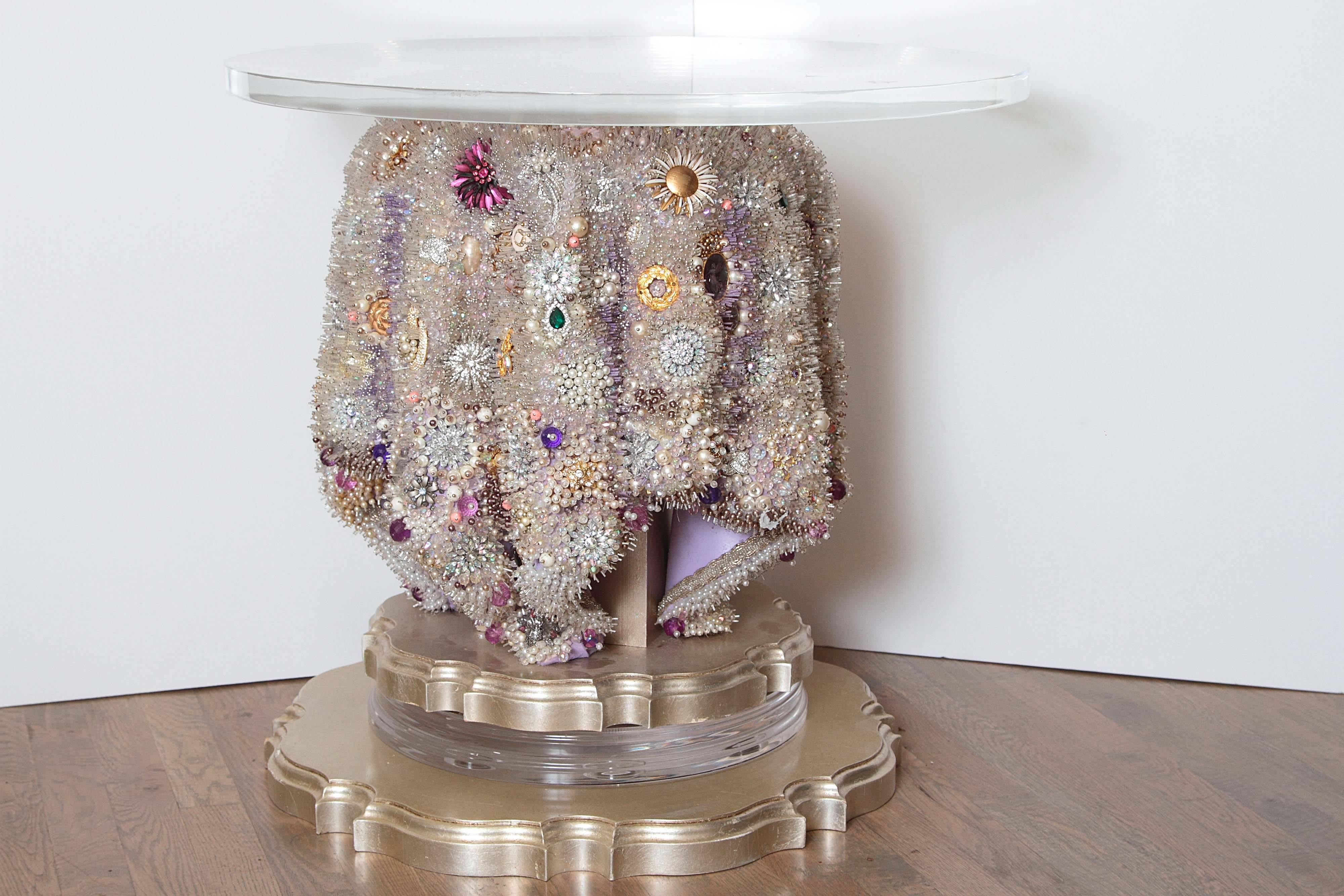 This one of a kind table is encrusted with over half a million glass seed beads, thousands of vintage and new beads and hundred of vintage brooches. This table was created to provide an illusion of beautiful beaded fabric draped over to create a