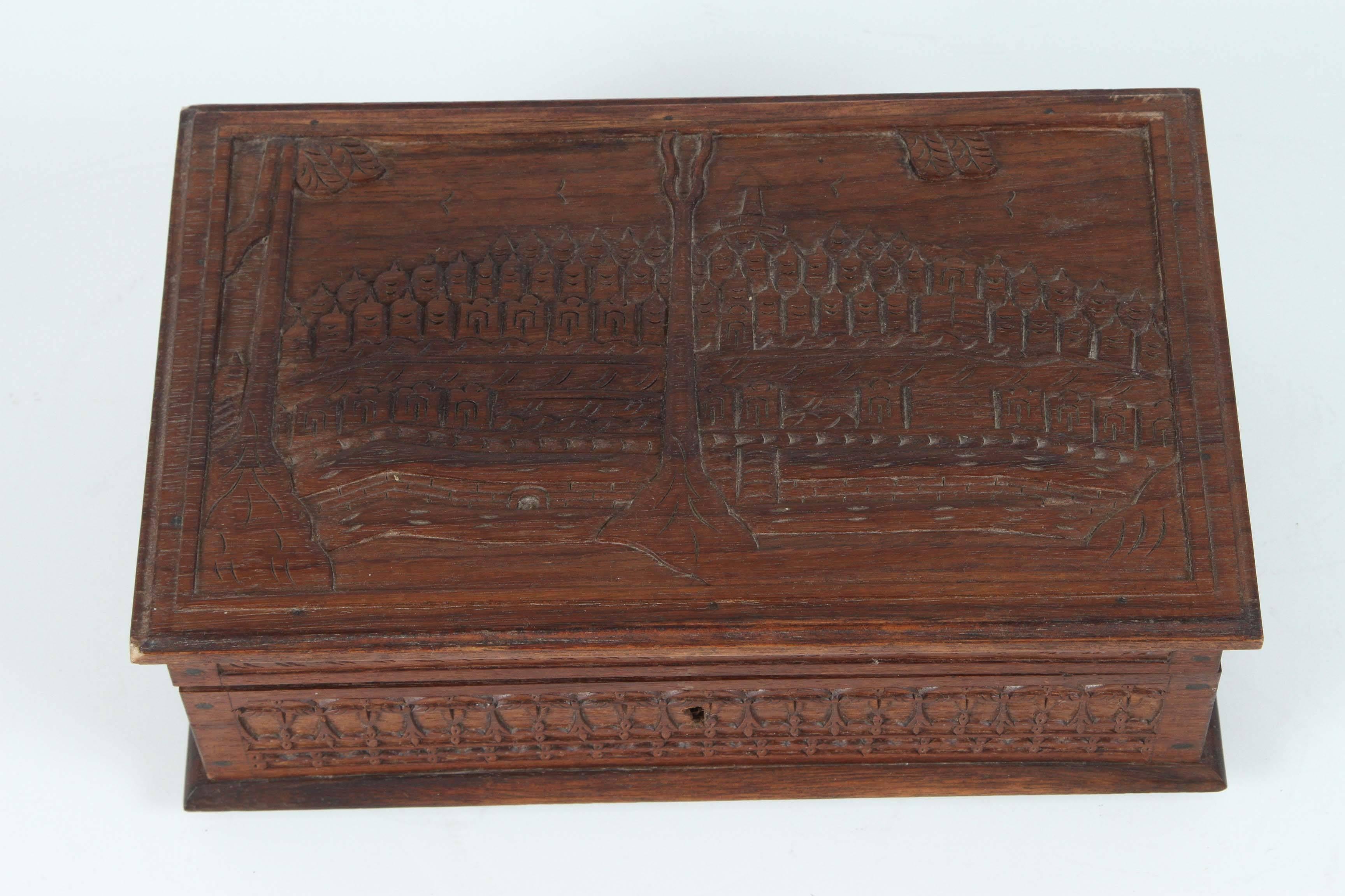 Nice handcrafted Anglo Indian hardwood jewelry box, handmade in India, foliage design on the side and the top is depicting a village in border of a river.
Inside is lined with blue velvet and there is a removable tray.
There is no key.