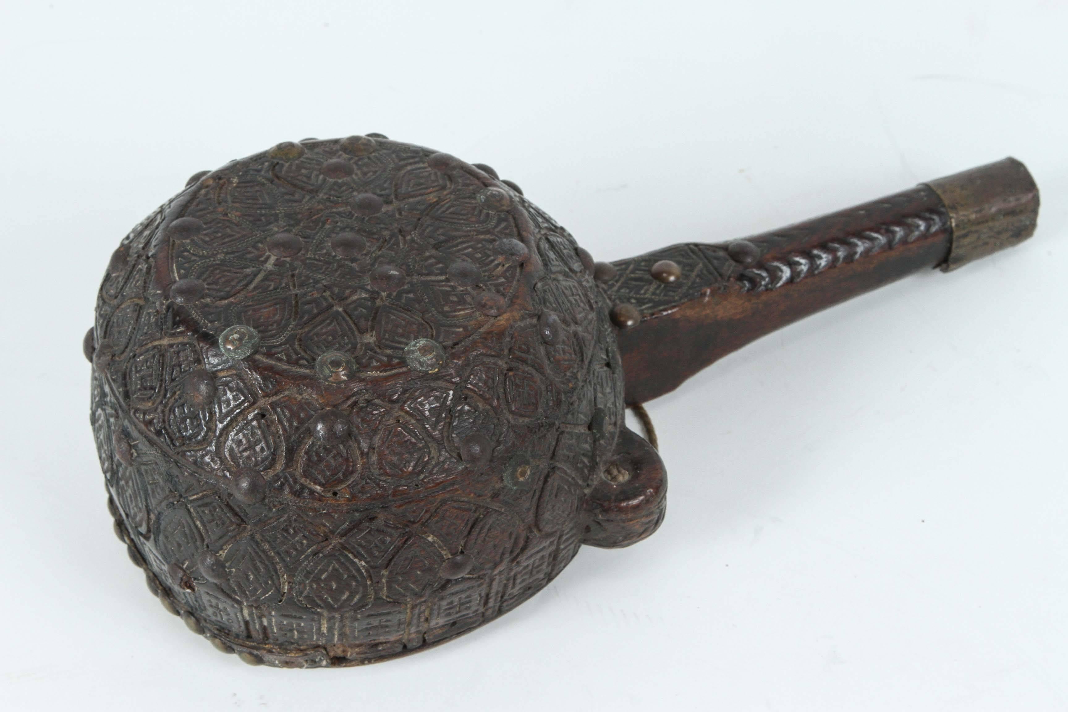 Moroccan tribal powder flasks.
19th century studded powder flasks in three different finely engraved designs. 
Collector powder flasks in large carved wooden vessel with brass, studded and leather covered.
One is shorter 10