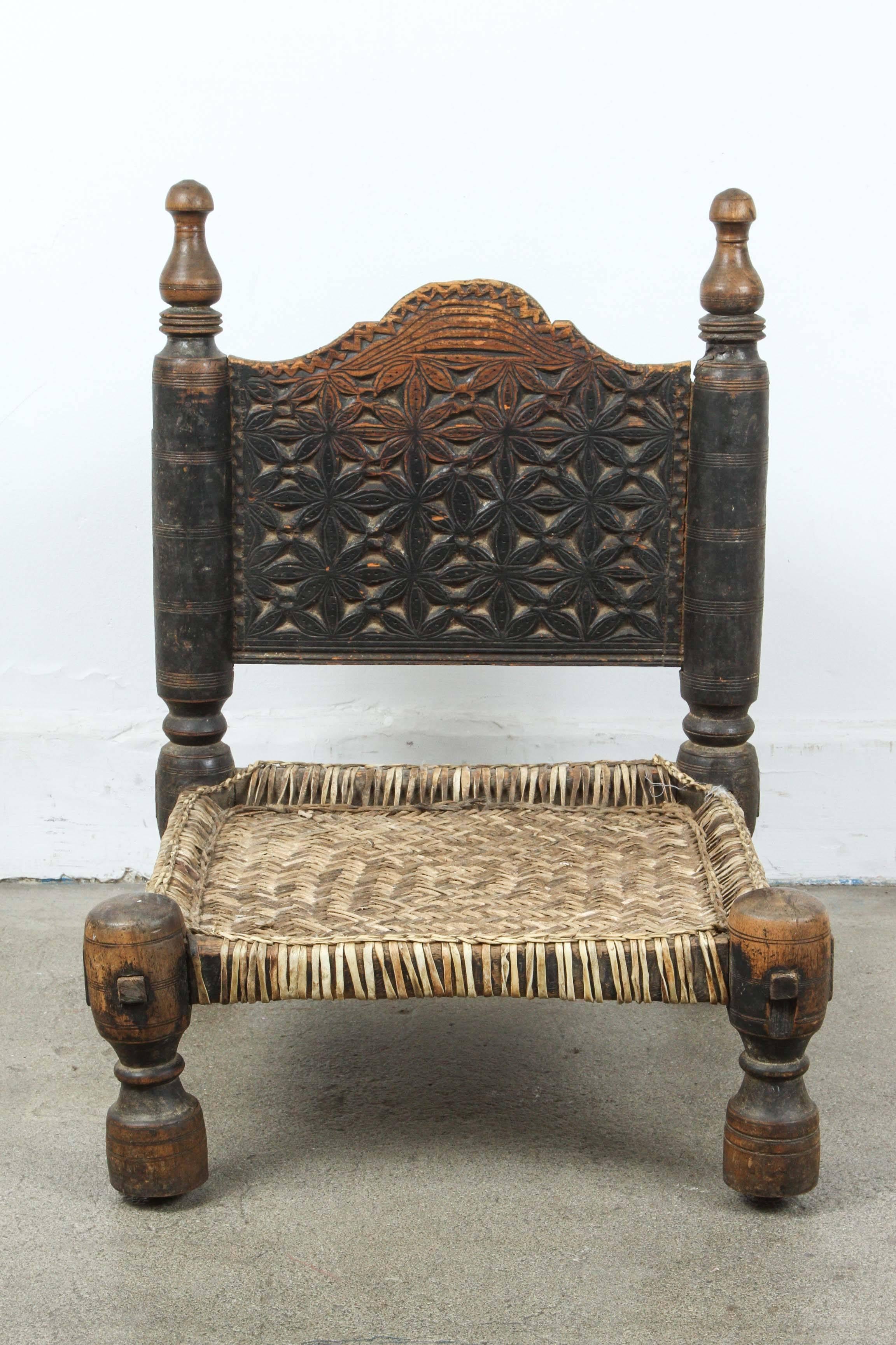 African low tribal chair, hand-carved with primitive design in the back and front, low turned legs.
The seat is made of woven leather.
