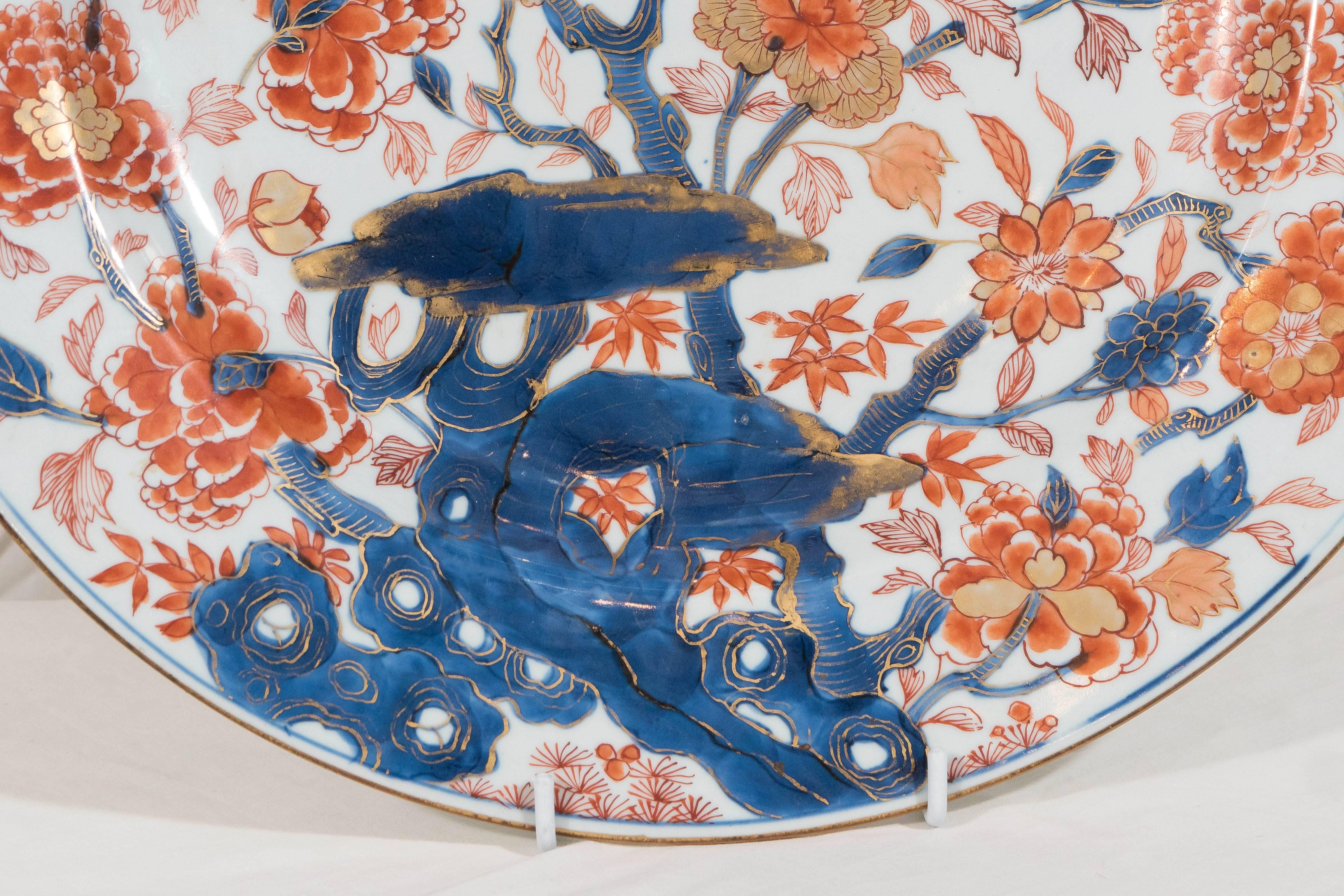 A beautiful 18th century Chinese porcelain charger in the Imari style.
Hand-painted in the traditional colors of underglaze blue, overglaze orange and gilt. The charger is fully decorated with an overall pattern showing a profusion of peonies and