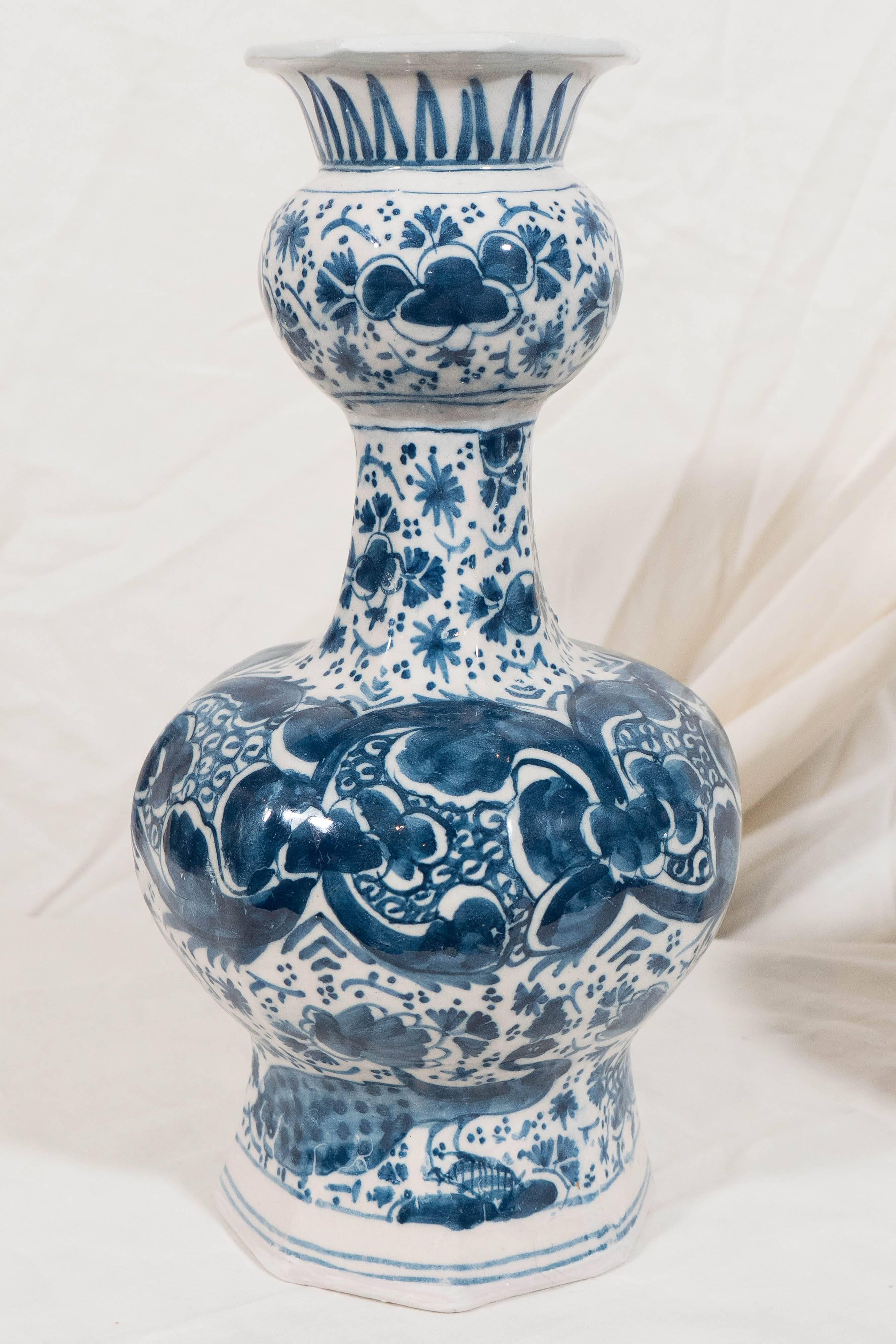A pair of small Dutch Delft Blue and White vases painted in deep cobalt with a design of flowers, leaves, scrolling vines and a pair of peacocks 