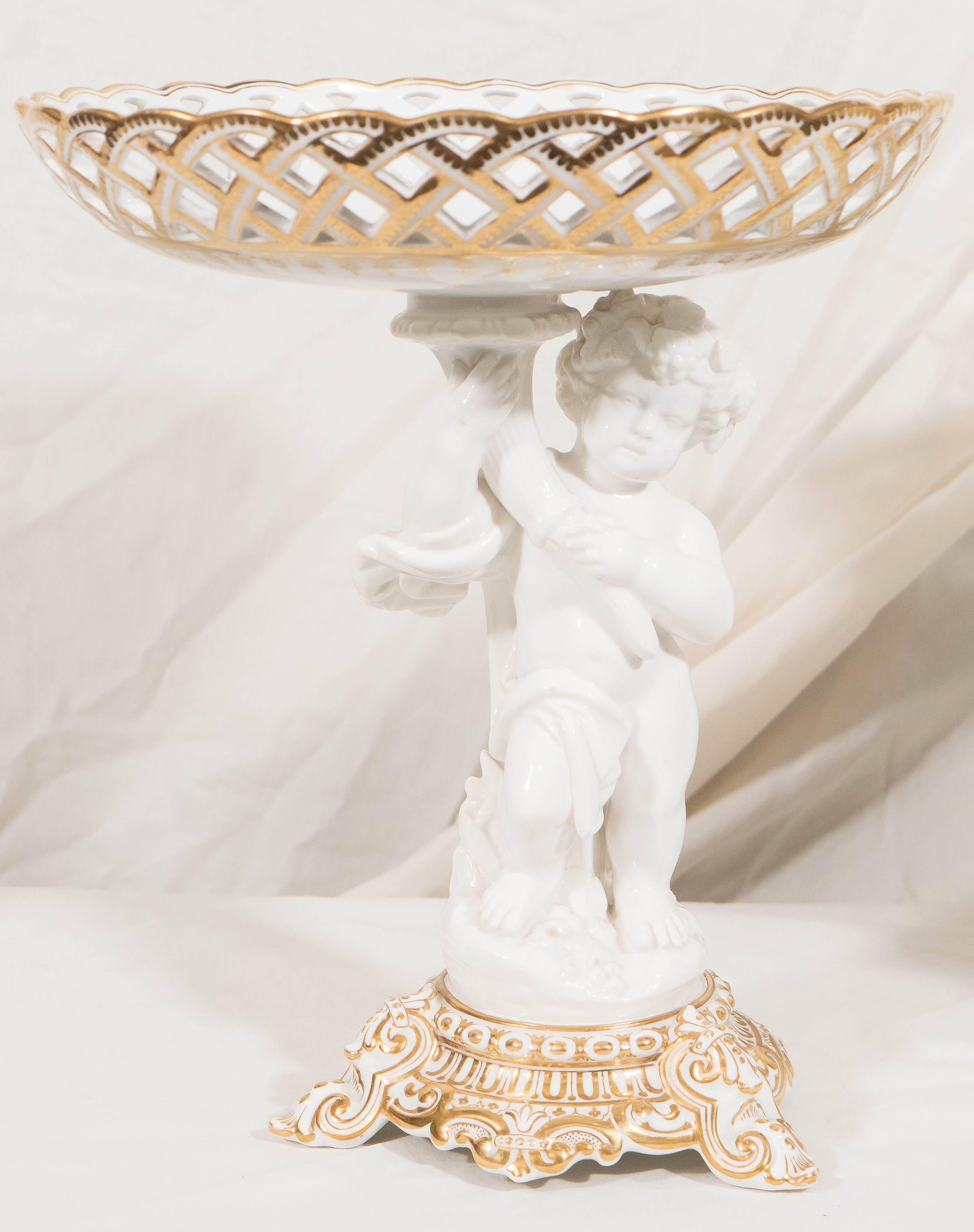 A model of a young boy holding a cornucopia supports the basket. The pierced baskets and the bases of these mid-19th century porcelain pieces were decorated with ornate gilding. Pairs of baskets like these were made to be filled with fruit or