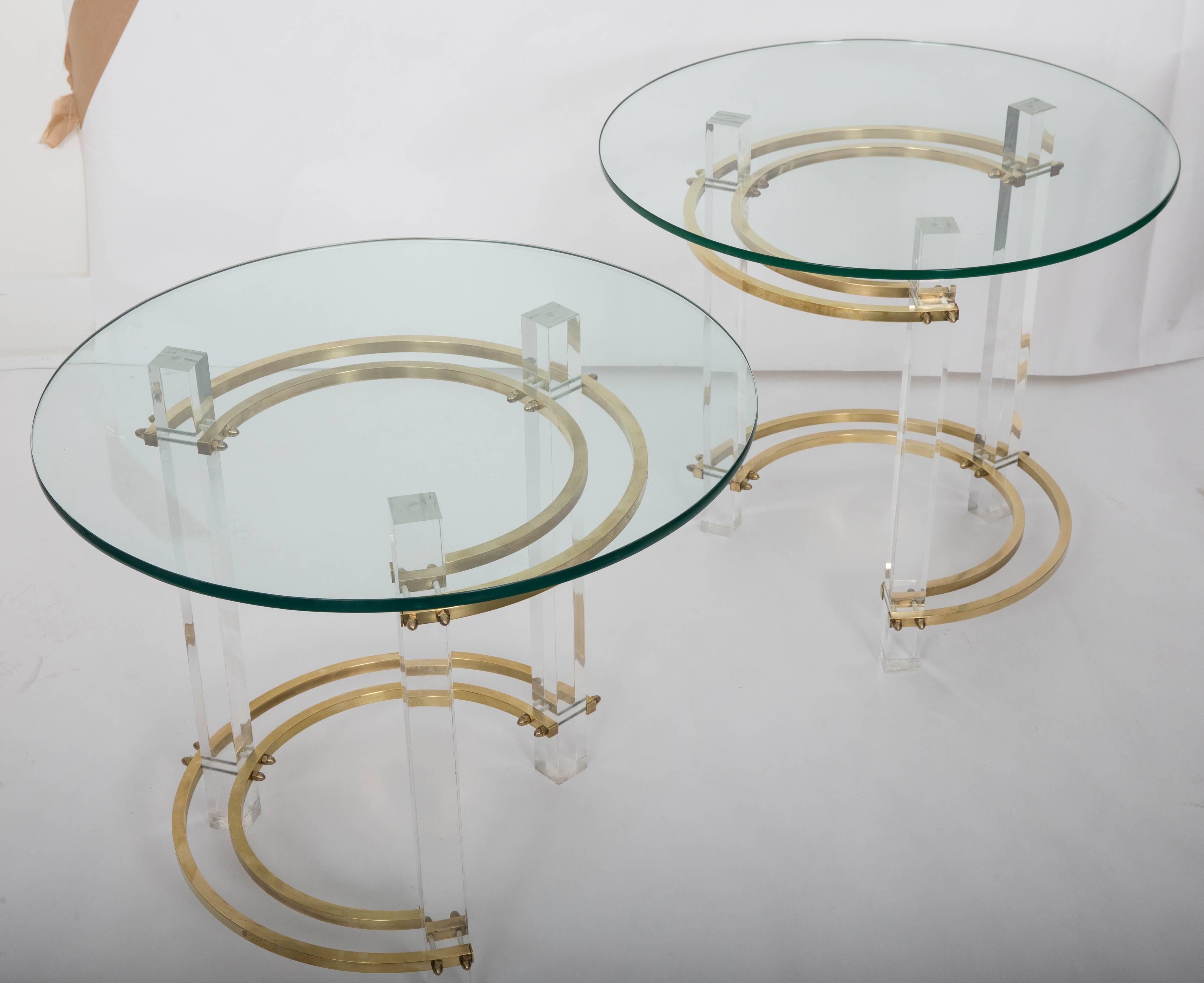 A pair of Mid-Century Modern round Lucite and brass side tables by Charles Hollis Jones. Each table is made of round brass and Lucite legs which support the glass tops. There are age appropriate scuffs marks and a small chip on one of the tables