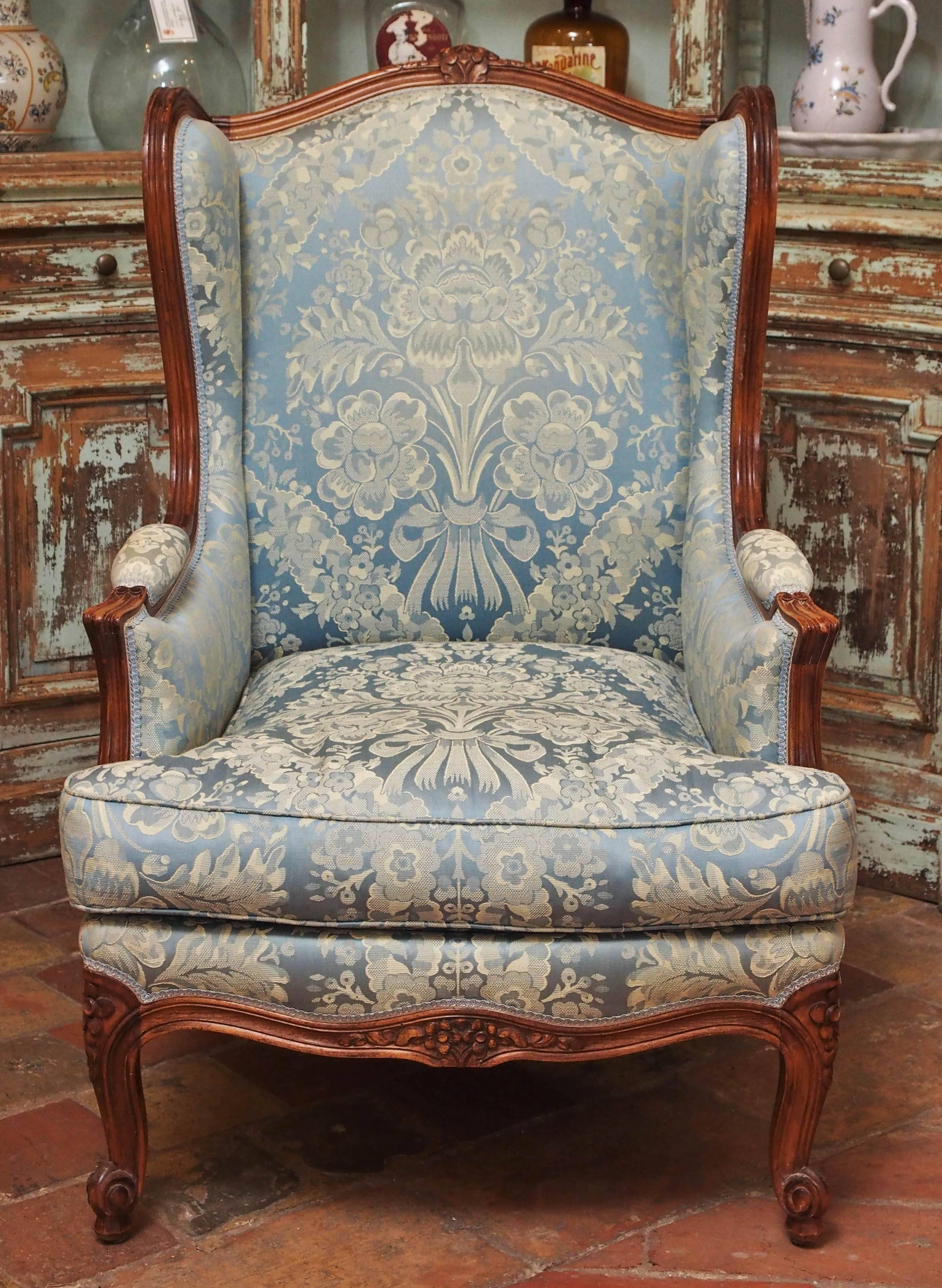 Pair of French walnut hand-carved Louis XV style bergere chairs upholstered in blue damask. This pair was purchased from a private estate in Provence, circa 1850.