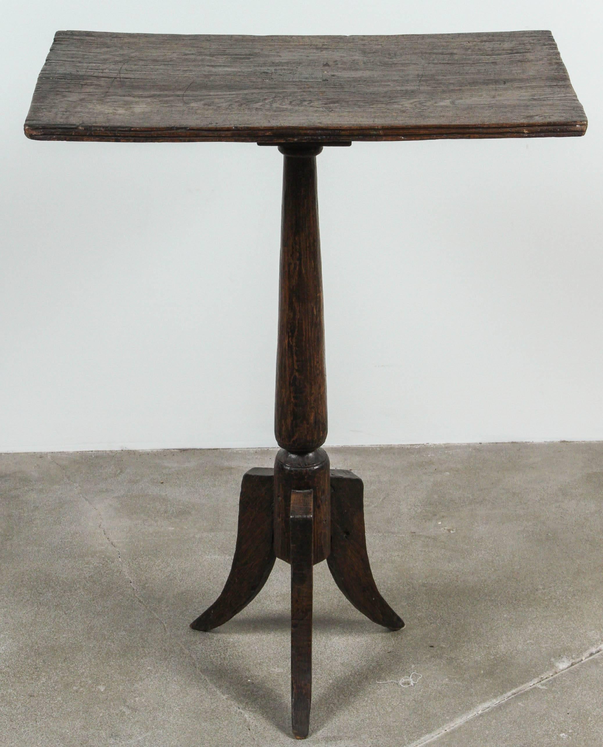 Dark stained Primitive pedestal side table with single pedestal and three splayed feet at base.