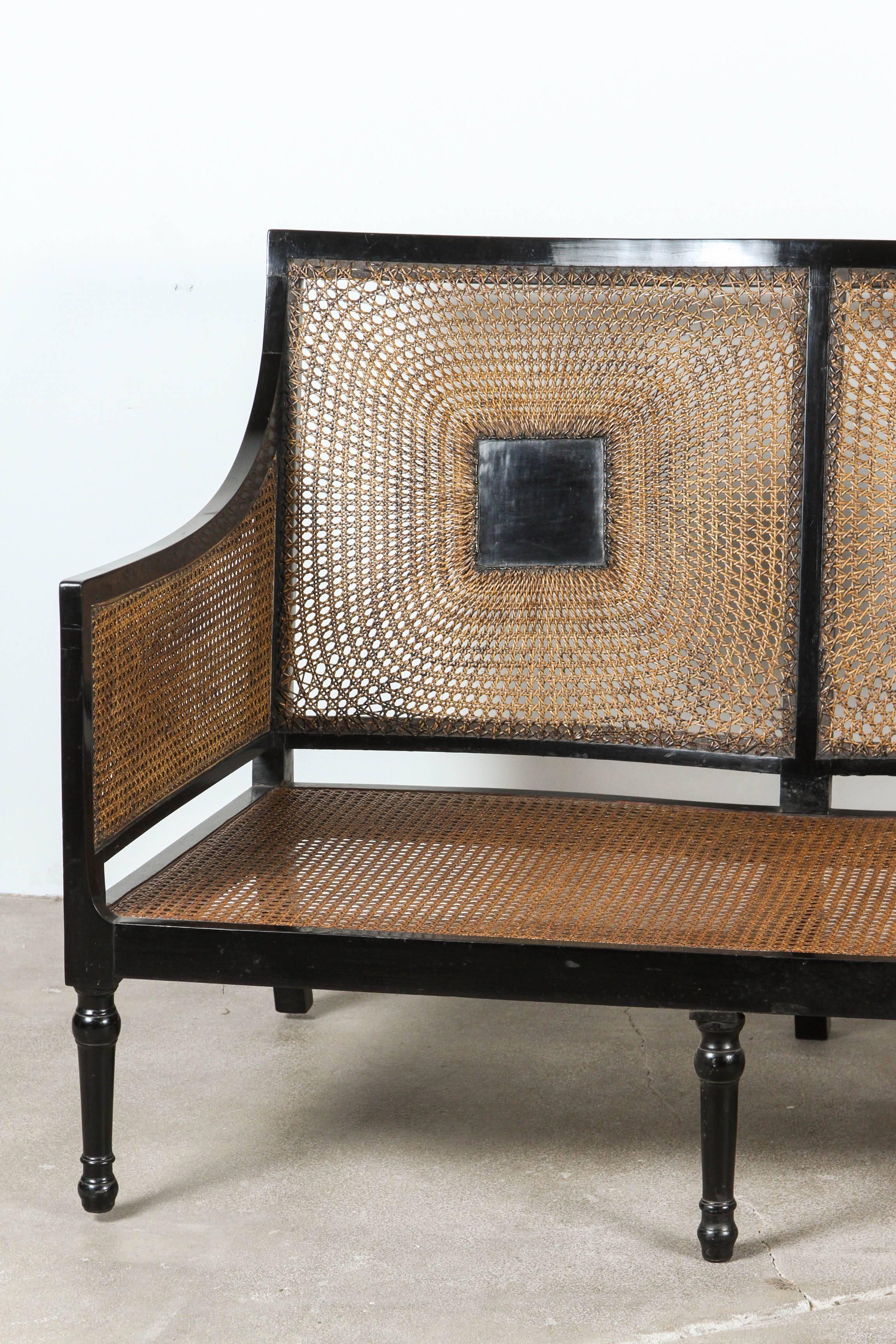 Italian black framed caned bench with intricate caned details on the back.