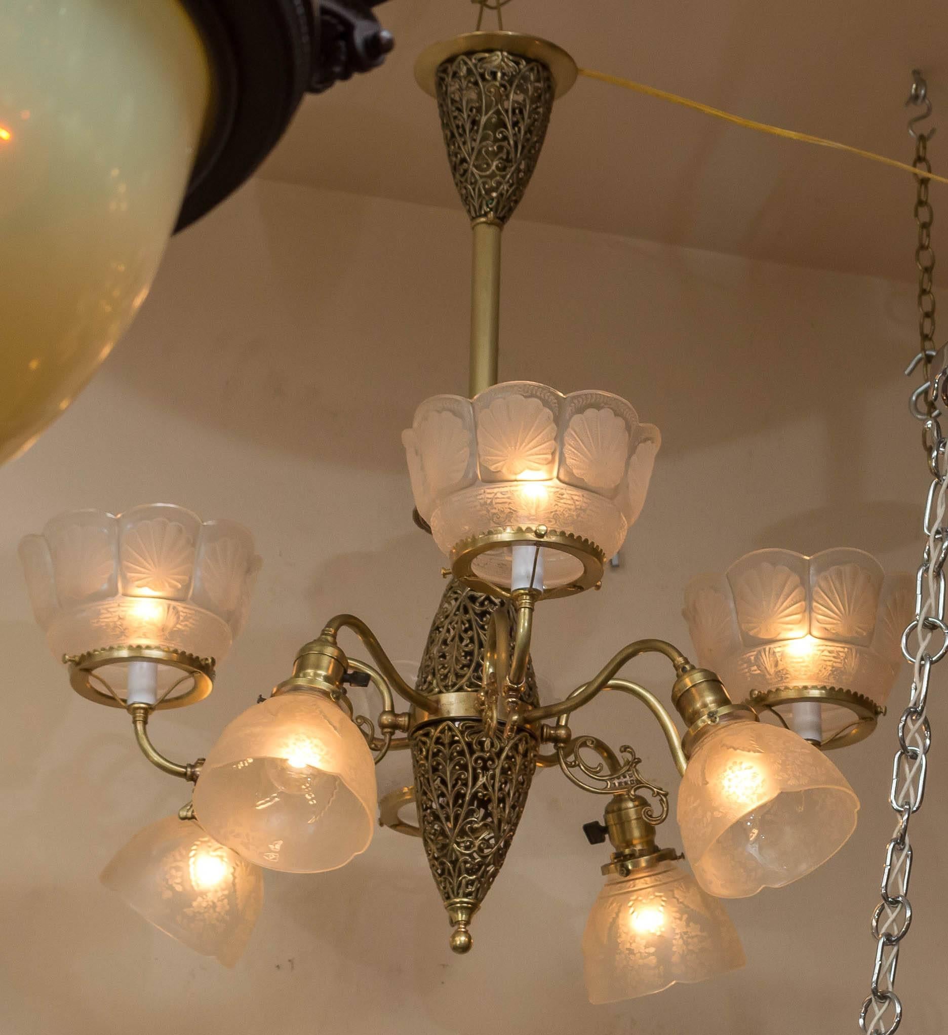 This late Victorian chandelier offers the desired pierced brass center as well as the beautiful deep etched period shades. The gas shades are particularly nice with a shell design. Chandeliers that offer up and down light are very popular and offer