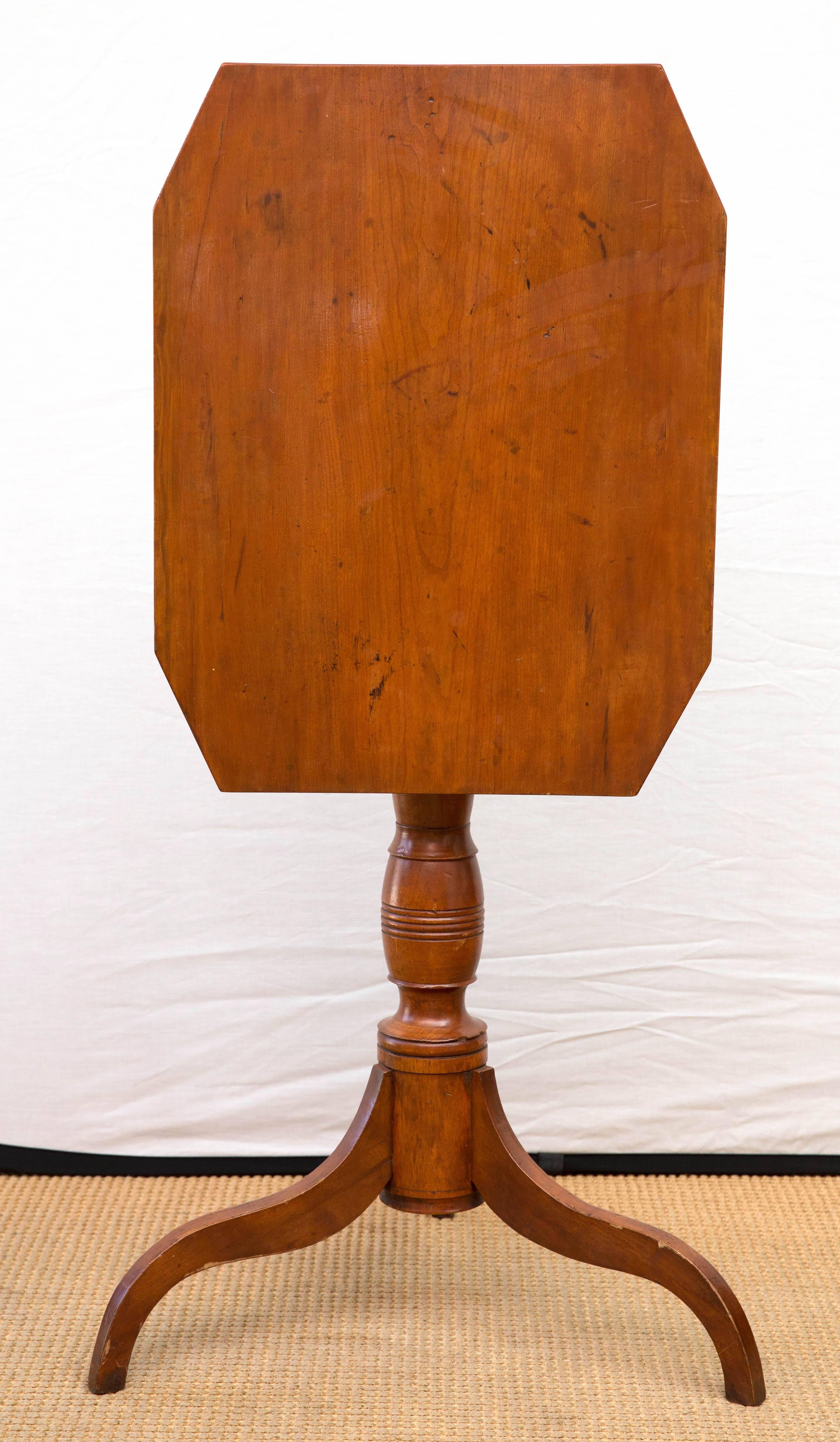 Federal walnut tilt-top candlestand. The rectangular cut-corner top on vase and ring-turned support and tripod base of shaped legs.