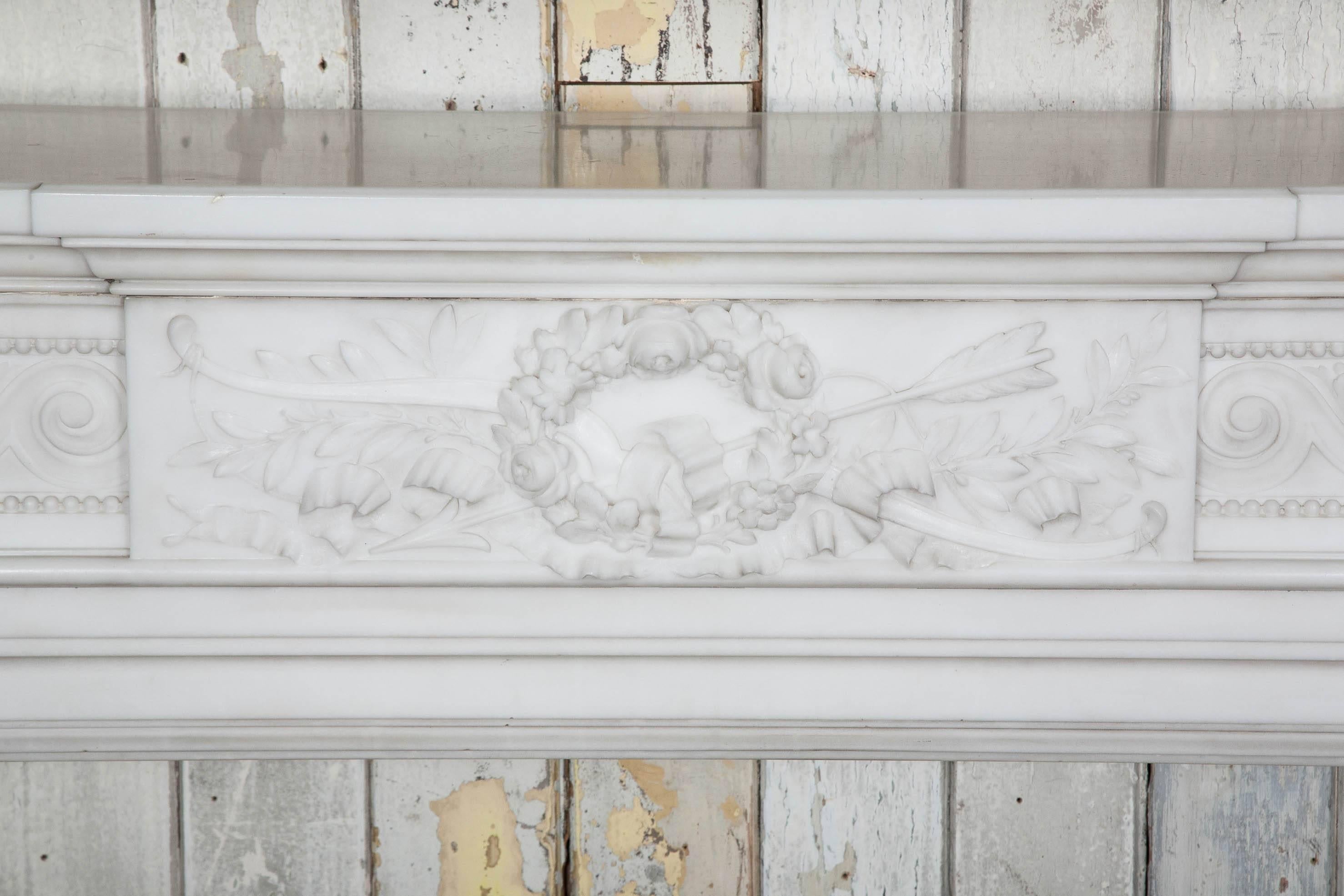 A pair of outstanding antique French style mantelpieces in white statuary marble. These original nineteenth century fireplace surrounds are in the Louis XVI manner, with palatial proportions and finely carved decoration. The paneled frieze features