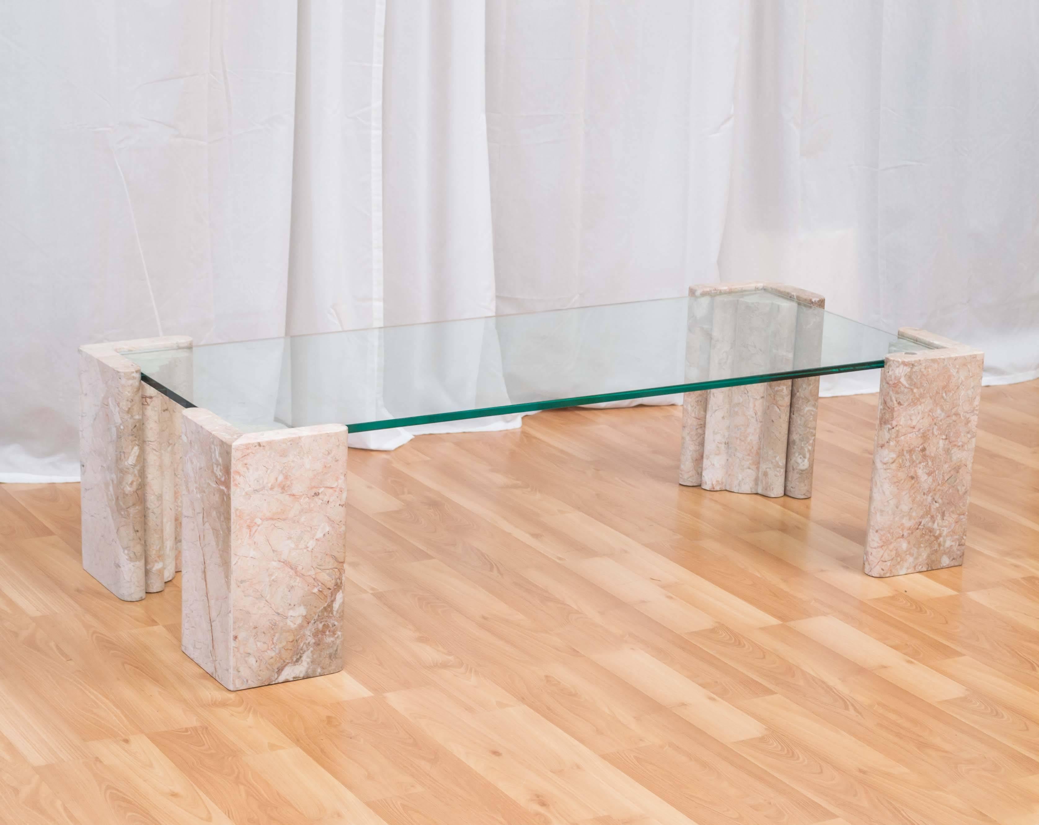 A large and architectural pale pink marble coffee table with glass top by Maitland-Smith. 

Base is comprised of four independent and substantial solid marble columns that have an Art Deco feel. Thick glass top sits on inset corners.