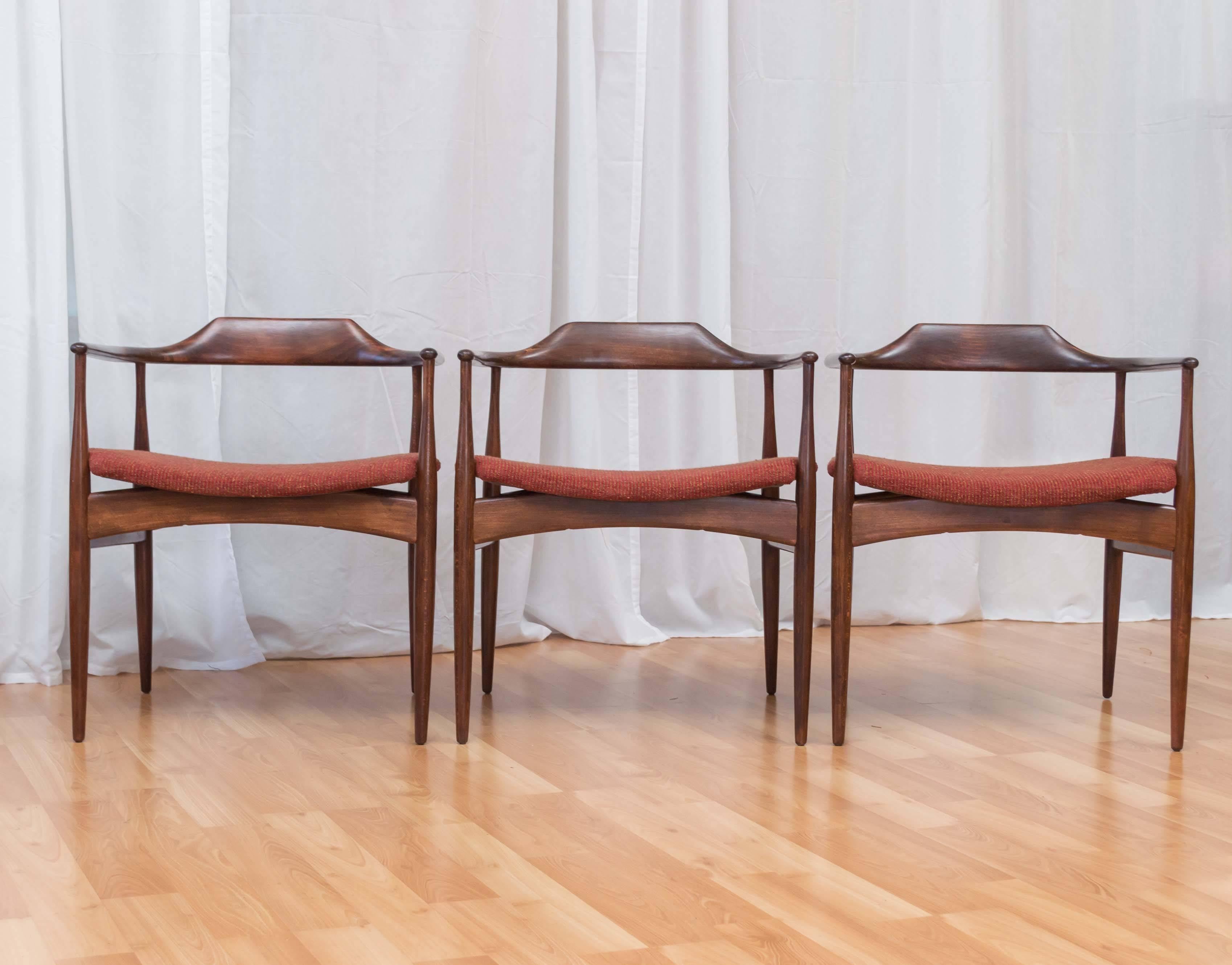 A six-piece set of generously-proportioned upholstered dining chairs with arms by Ib Kofod-Larsen for Selig.

Frames are expertly crafted out of solid beech, with a glossy raw-to-burnt umber finish that highlights their lively grain and sweeping