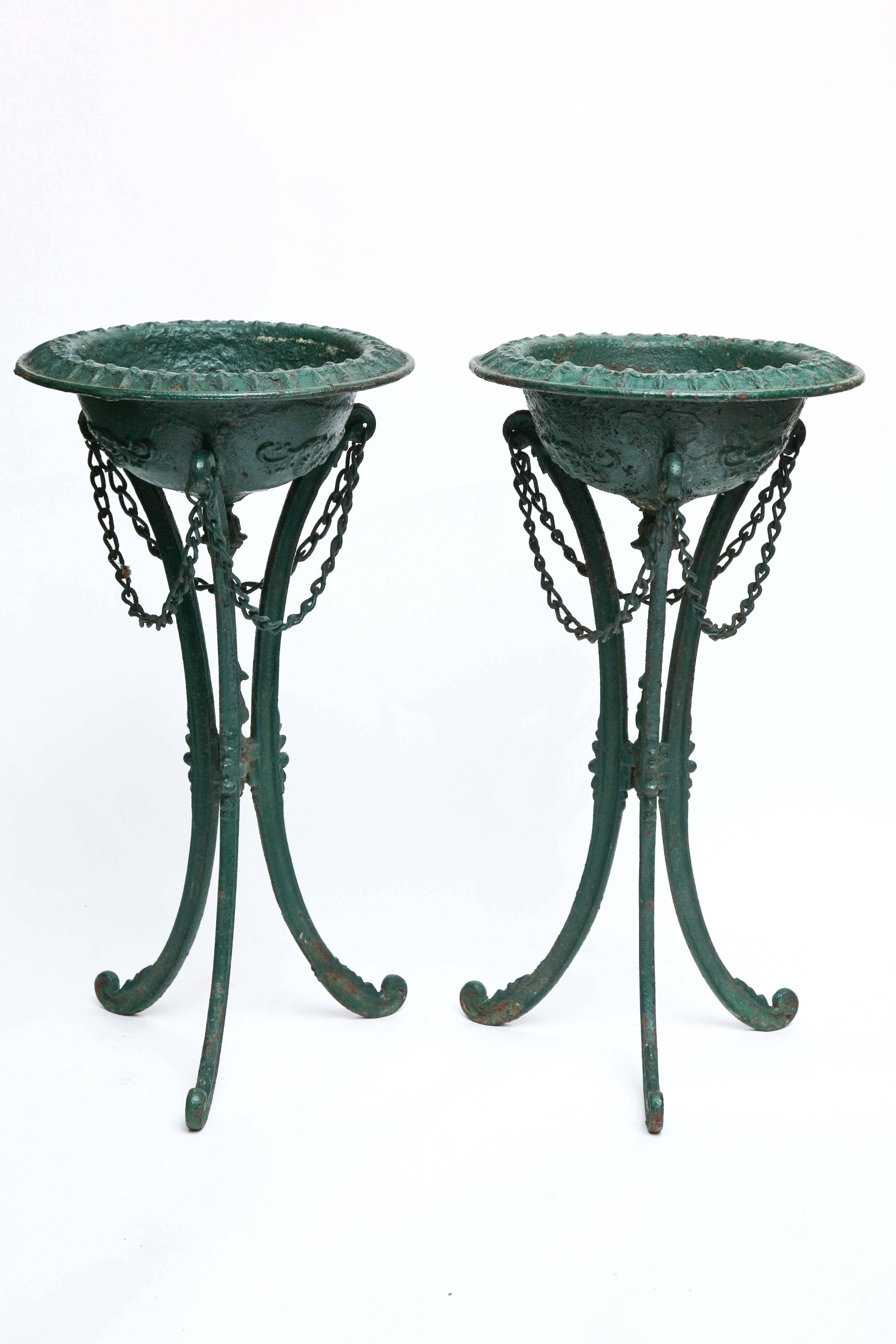 A rare find. The pair of "pots" are appointed with a border of fleur-de-lis raised on an unusual tripod base with swags of chains.