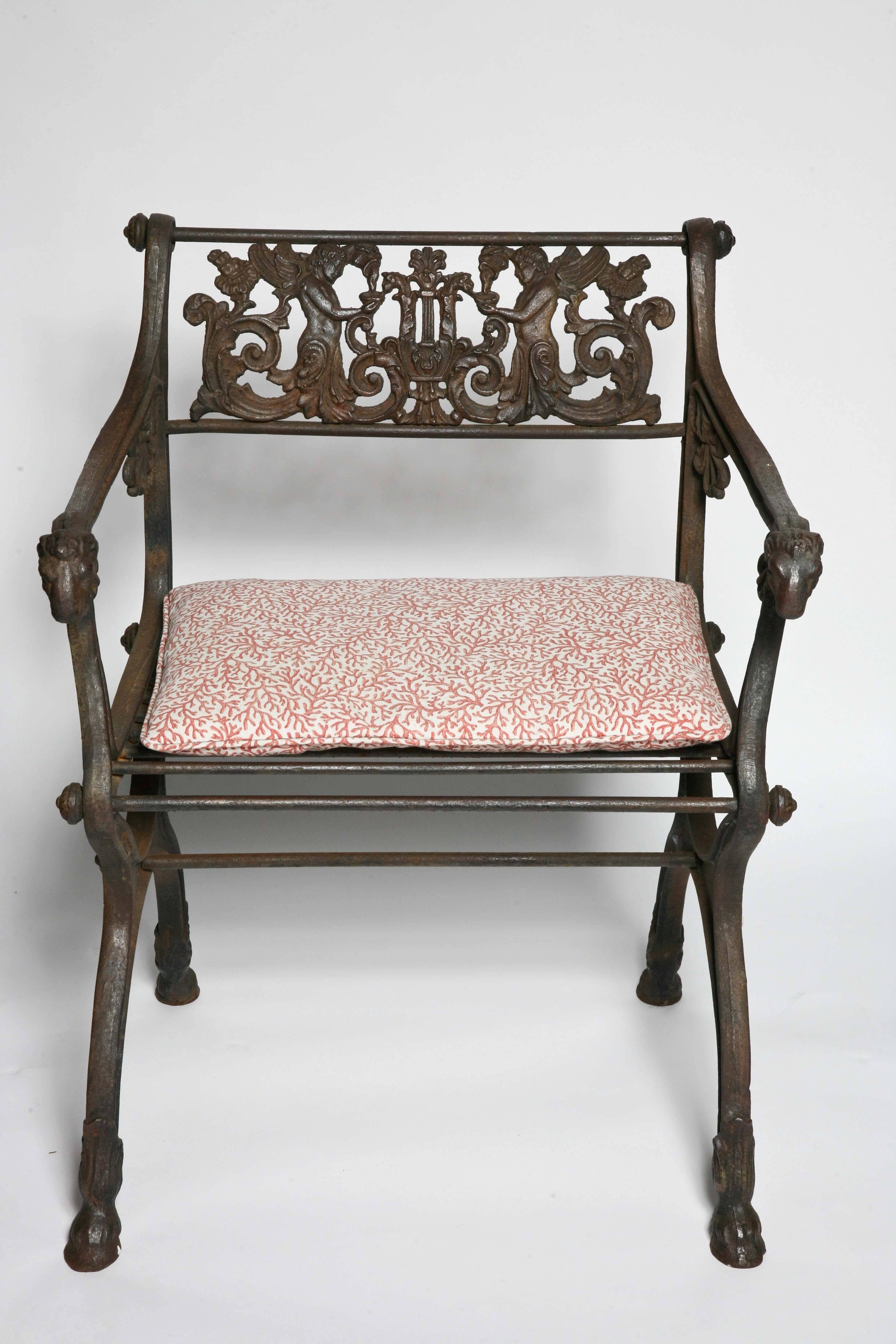Pair of heavy cast iron arm chairs, classical design with winged cherubs adorning the back rest and arm rest adorned with 