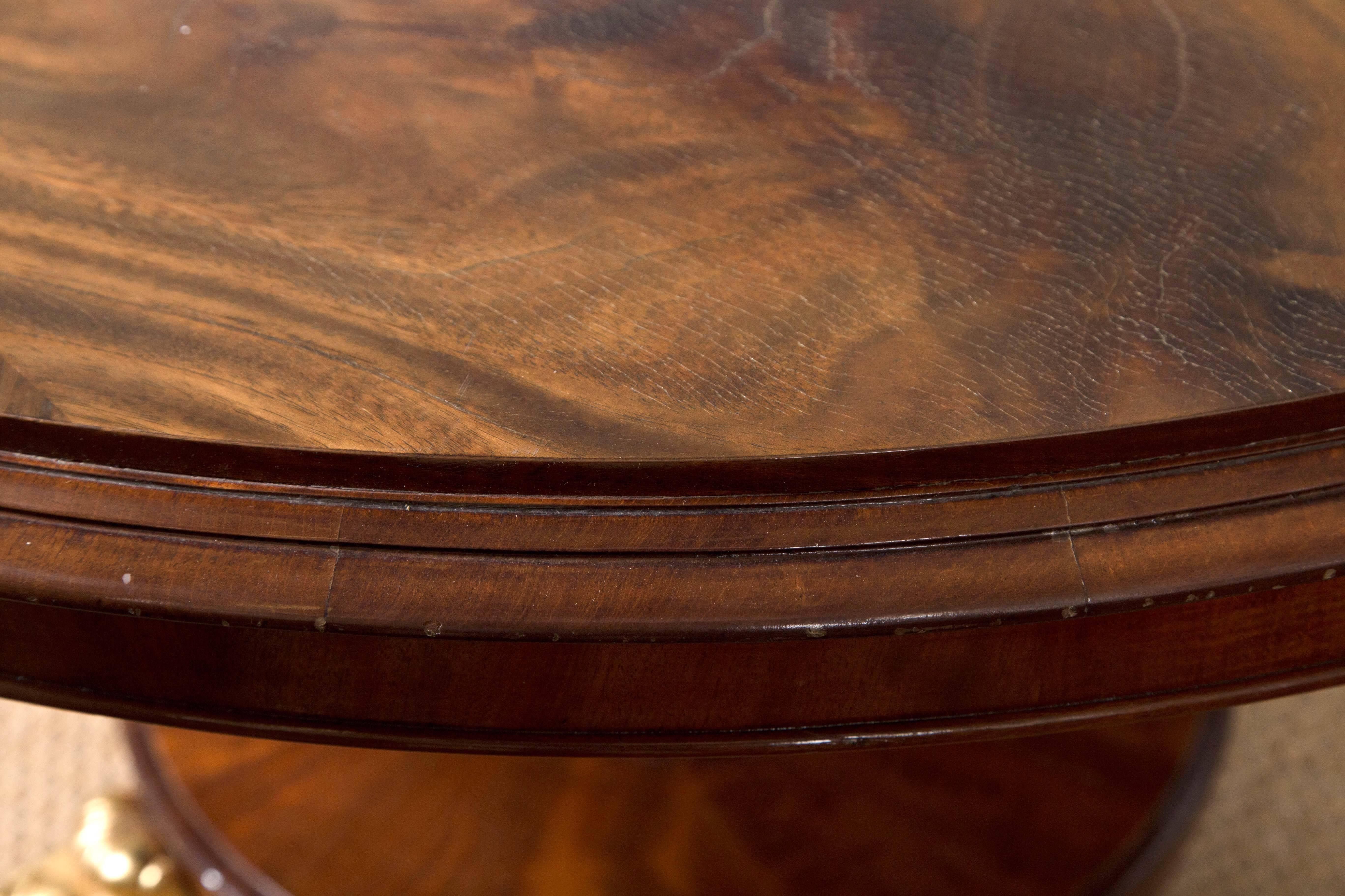 This tilt top center or breakfast table, has four gilt scroll feet below the base. Octagonal pedestal with black and gilt decoration. The top in need of refinishing. Molded edge of the top makes the surface area 48 inches in diameter.
