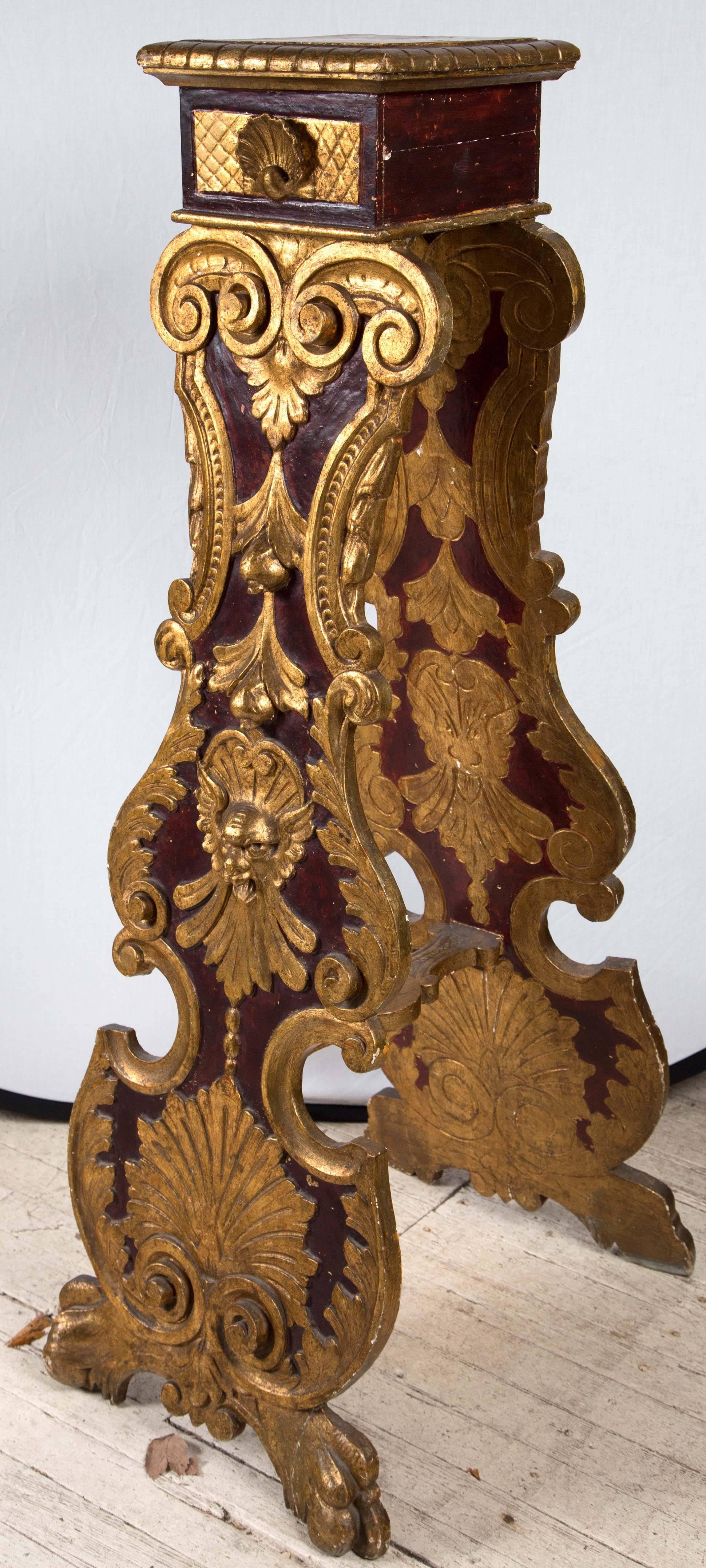 A splayed leg pedestal or plant stand painted in dark red faux bois and with gilded hand carvings with masks, leaf designs, scrolls, shells and gilt feet.
The back sides of each 