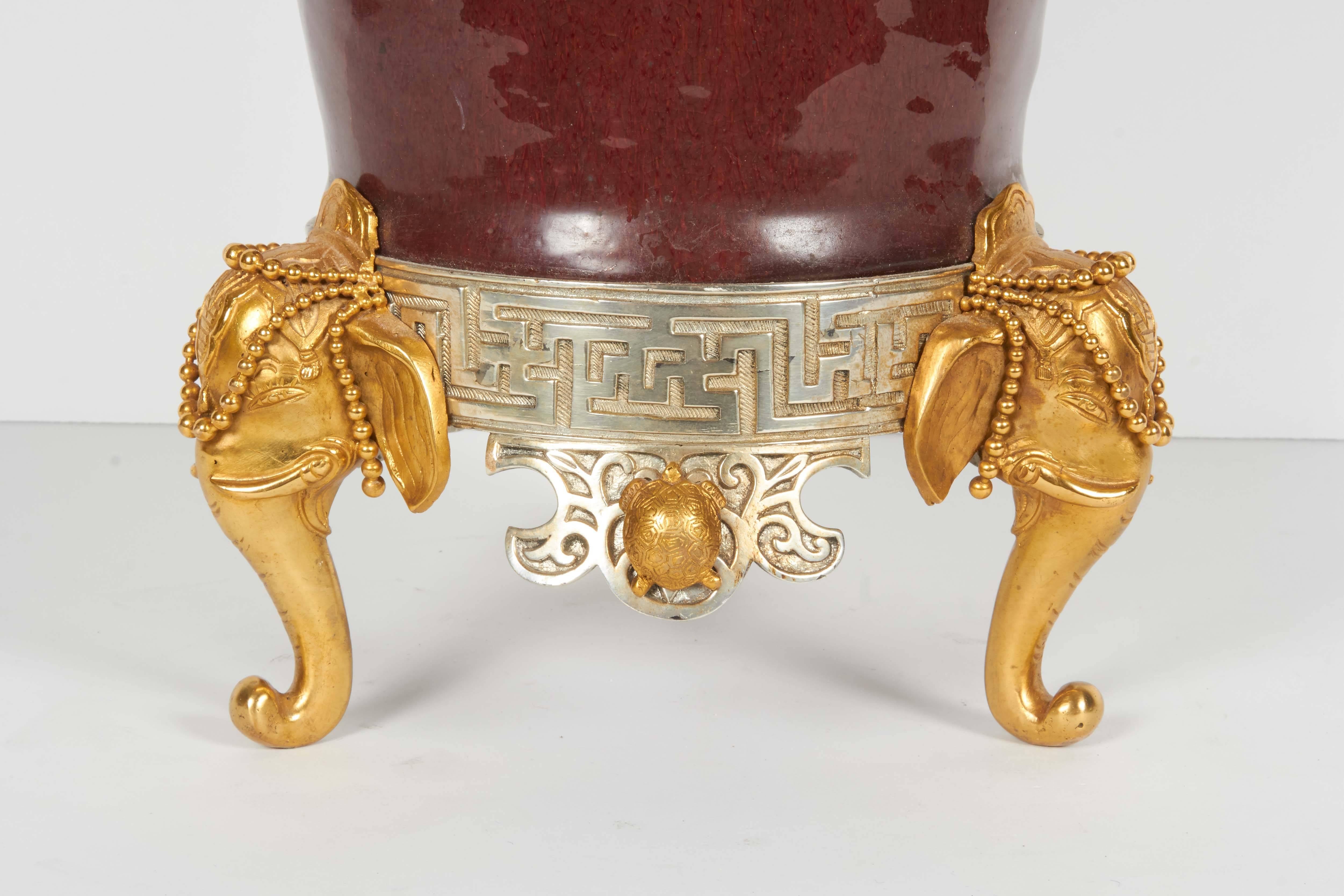 French Japonisme ormolu-mounted and silvered bronze Chinese porcelain ox blood red vase.

Late 19th century.

With bronze elephant support heads.

