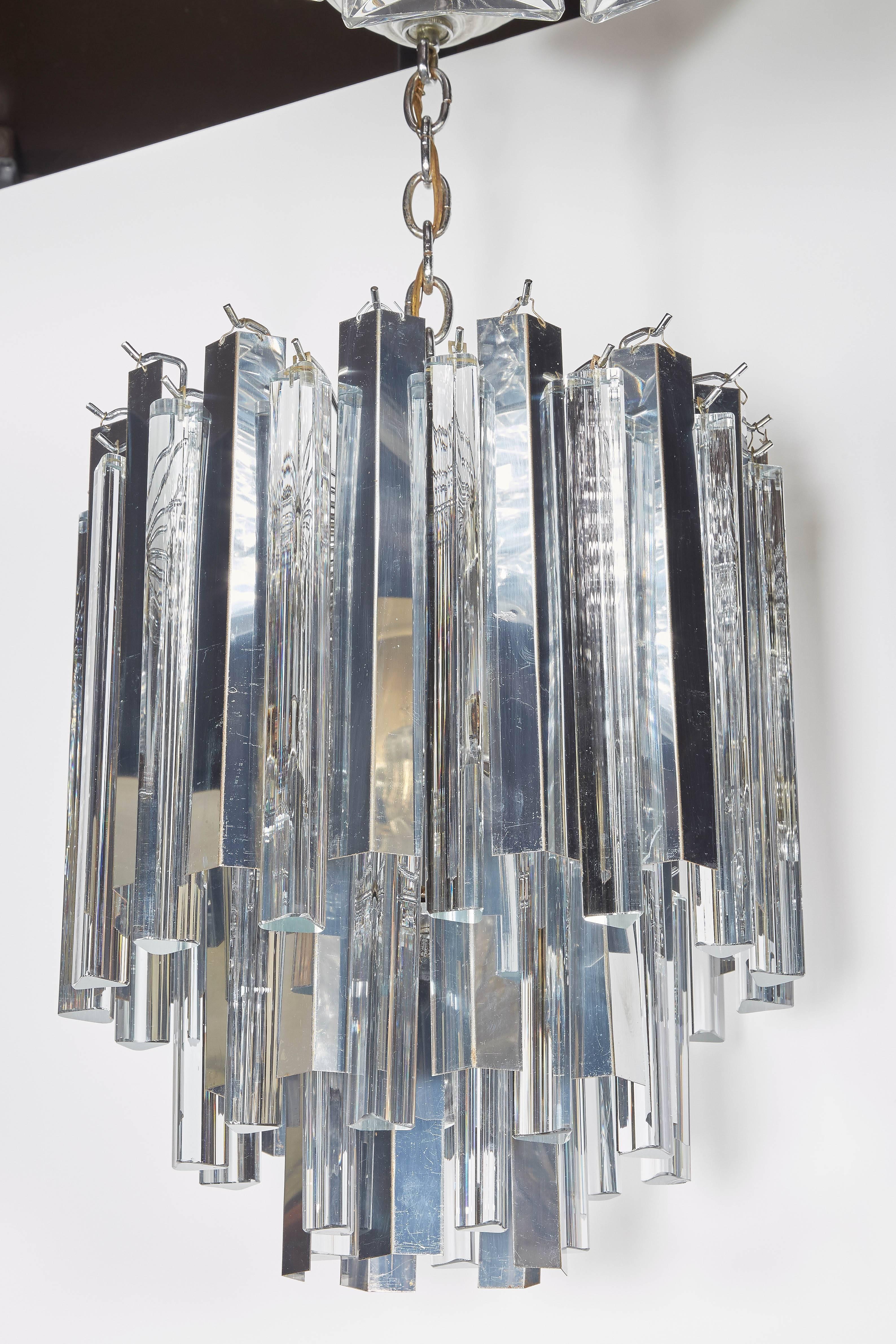 Rare modernist chandelier with multi-tier design, comprised of Murano glass prisms with triedre (three-sided) design and alternating polished chrome pendants. Fitted with 11 lights, (10 interior lights and 1 down light). The chandelier has steel