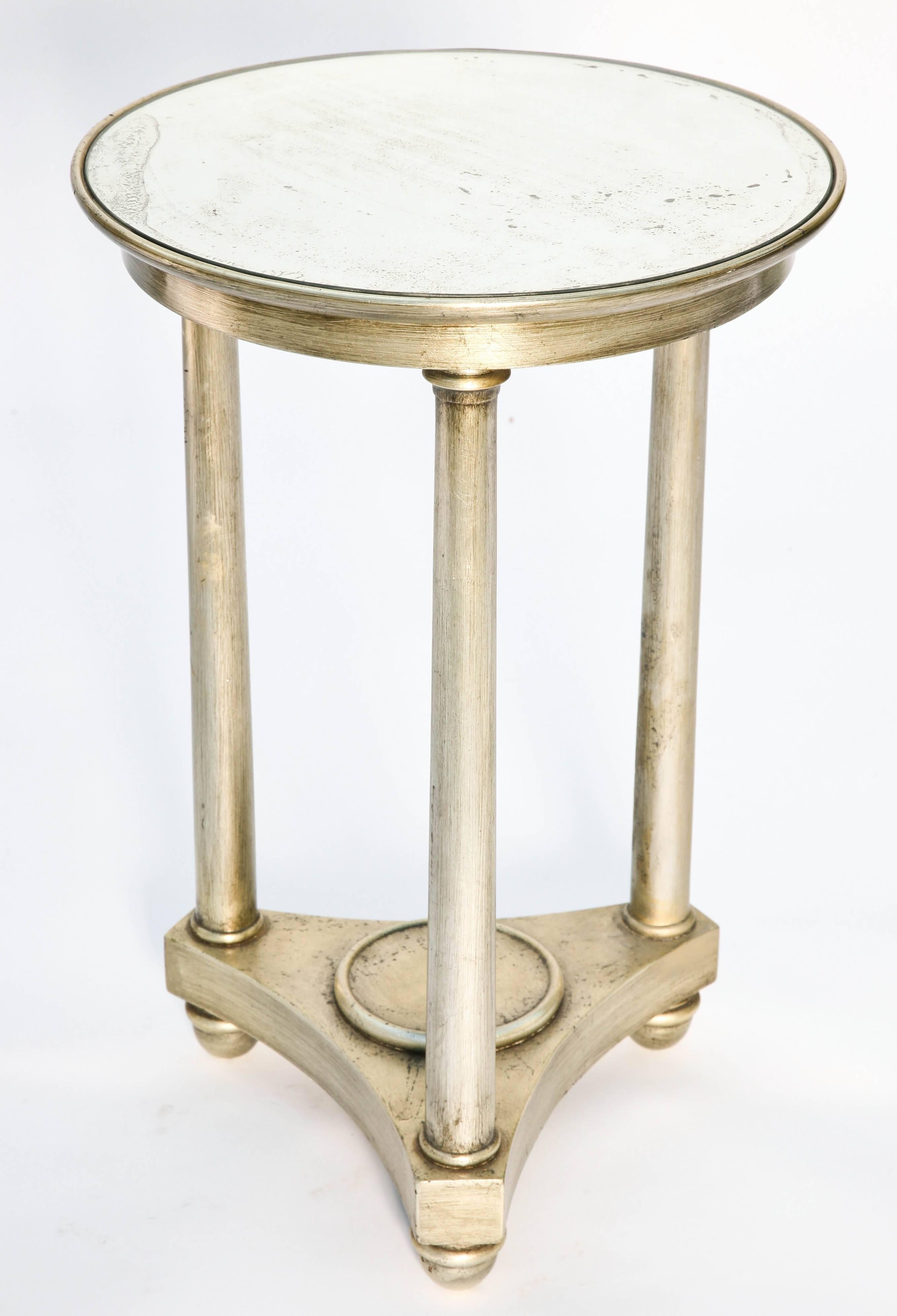 Round table, in Empire taste, of silver giltwood, having distressed mirrored top inset in frame, raised on three round column form legs on tripartite base, on bun feet.

Stock ID: D3838