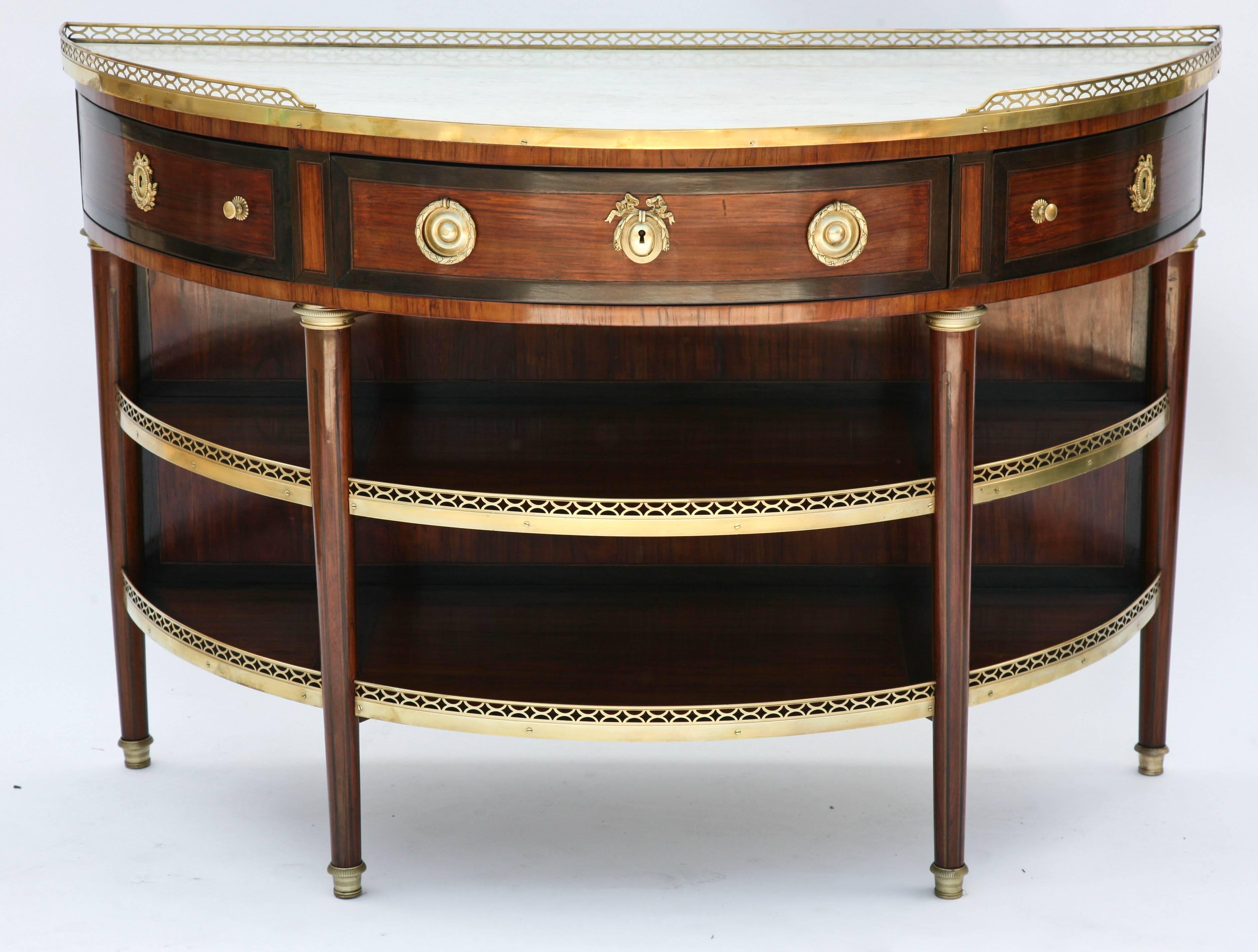 A fine pair of Louis XVI mahogany console dessértes, each having a pierced 3/4 quarter gallery and white marble top, above a single frieze drawer and two smaller drawers, all trimmed with crossbanding, having ormolu pulls and escutcheons, raised on