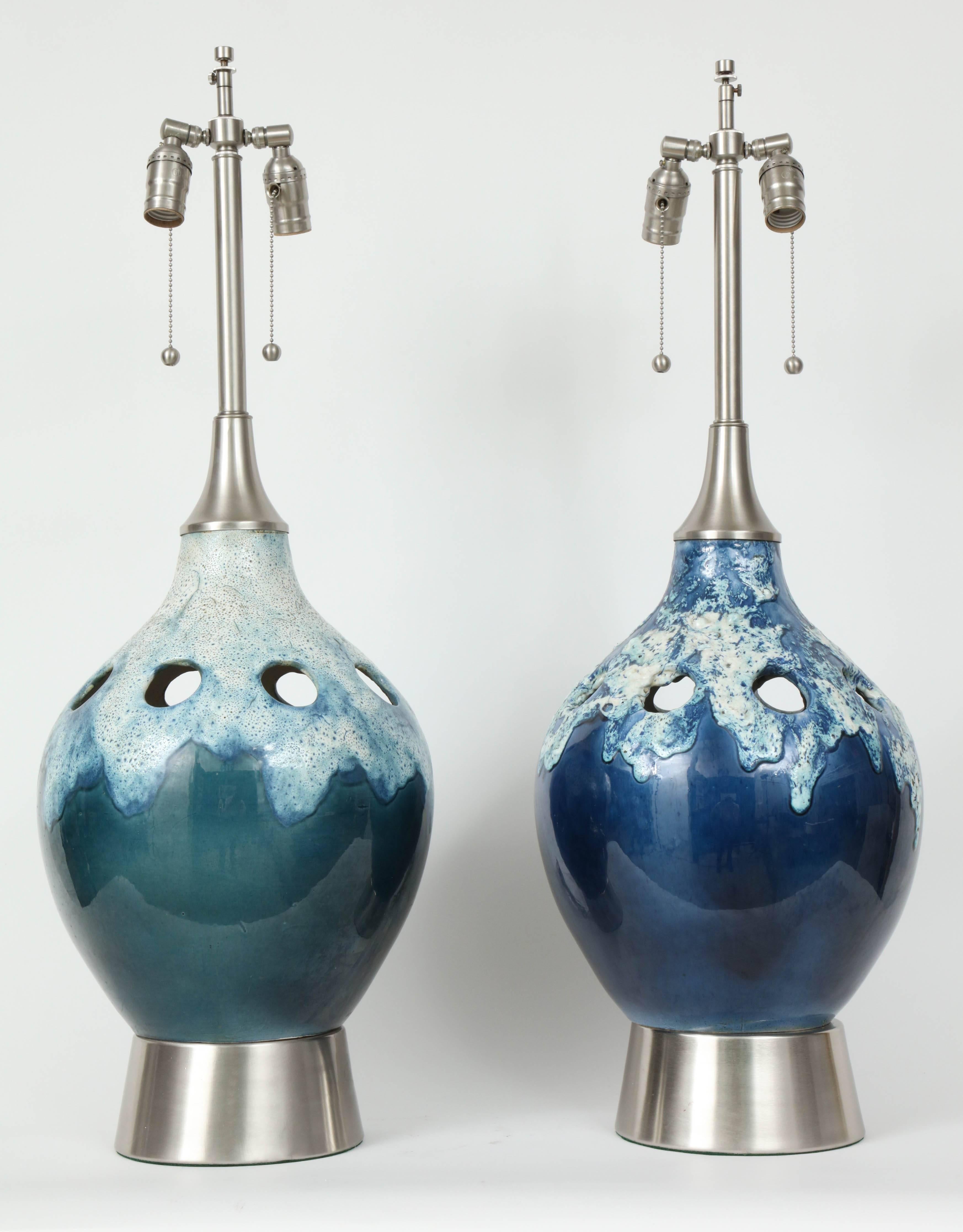 Pair of impressive scale ceramic lamps in tones of blue and green with white froth lava glaze overlay and pierced detail. Lamps sit on satin nickel bases and have satin nickel collars. Rewired for use in the USA with double pull chain sockets.