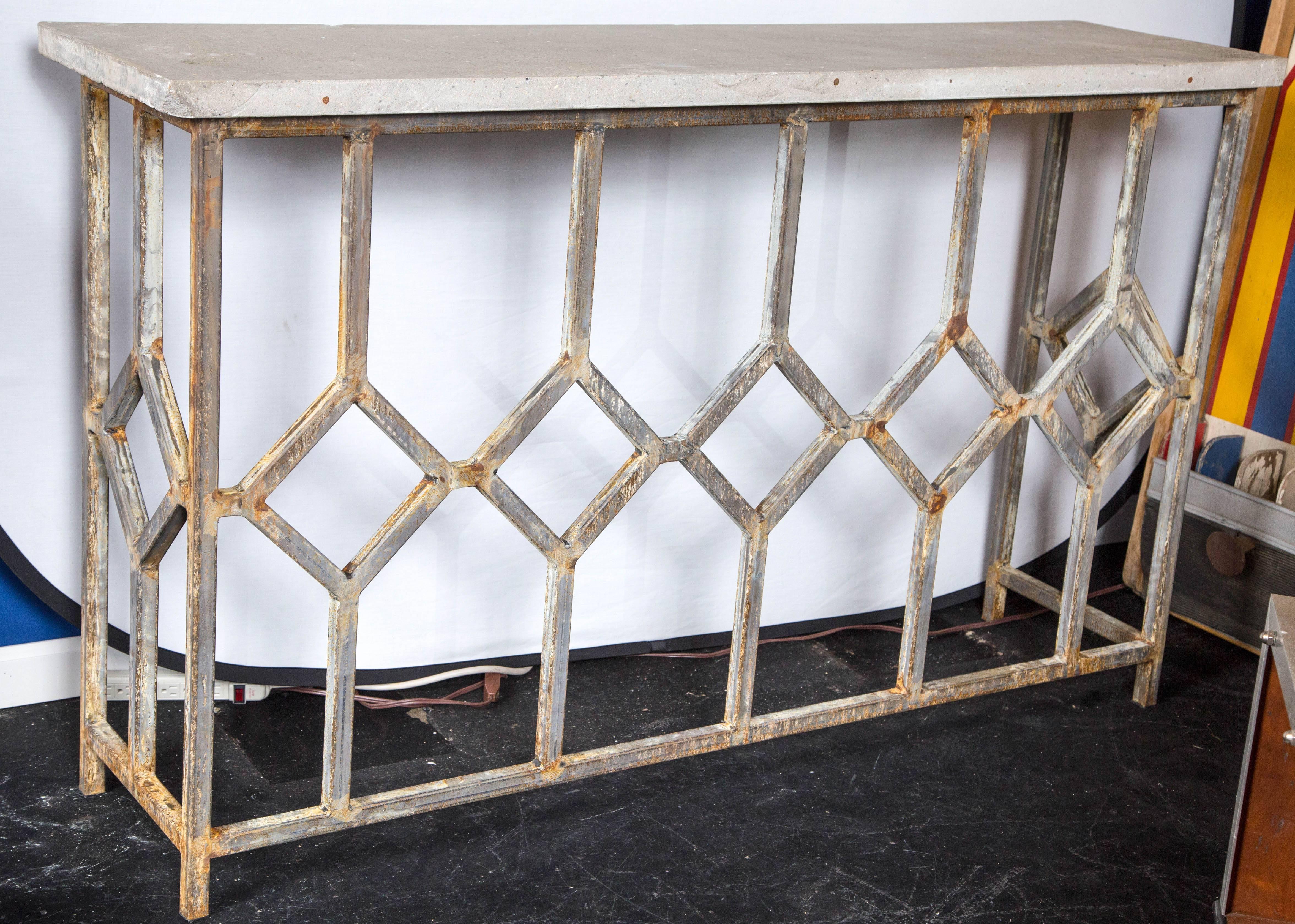 A unique hallway console table made from welded square steel tubing in an intricate pattern reminiscent of the deco period. The top is polished cement with minor imperfections.