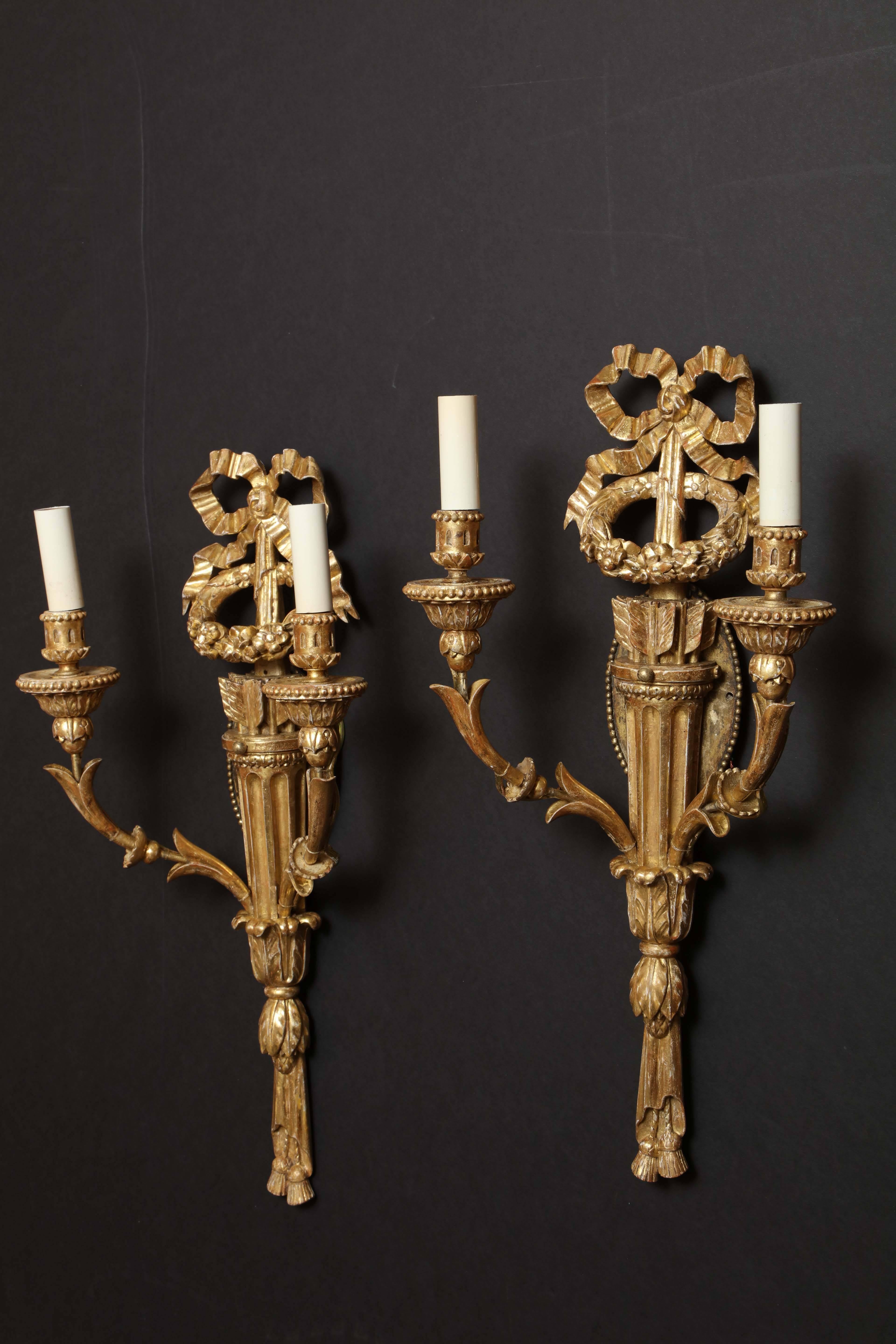 Una bella coppia di appliques Luigi XVI in legno dorato intagliato con nodi d'arco, frecce, faretre e acanto intagliato e nappe.