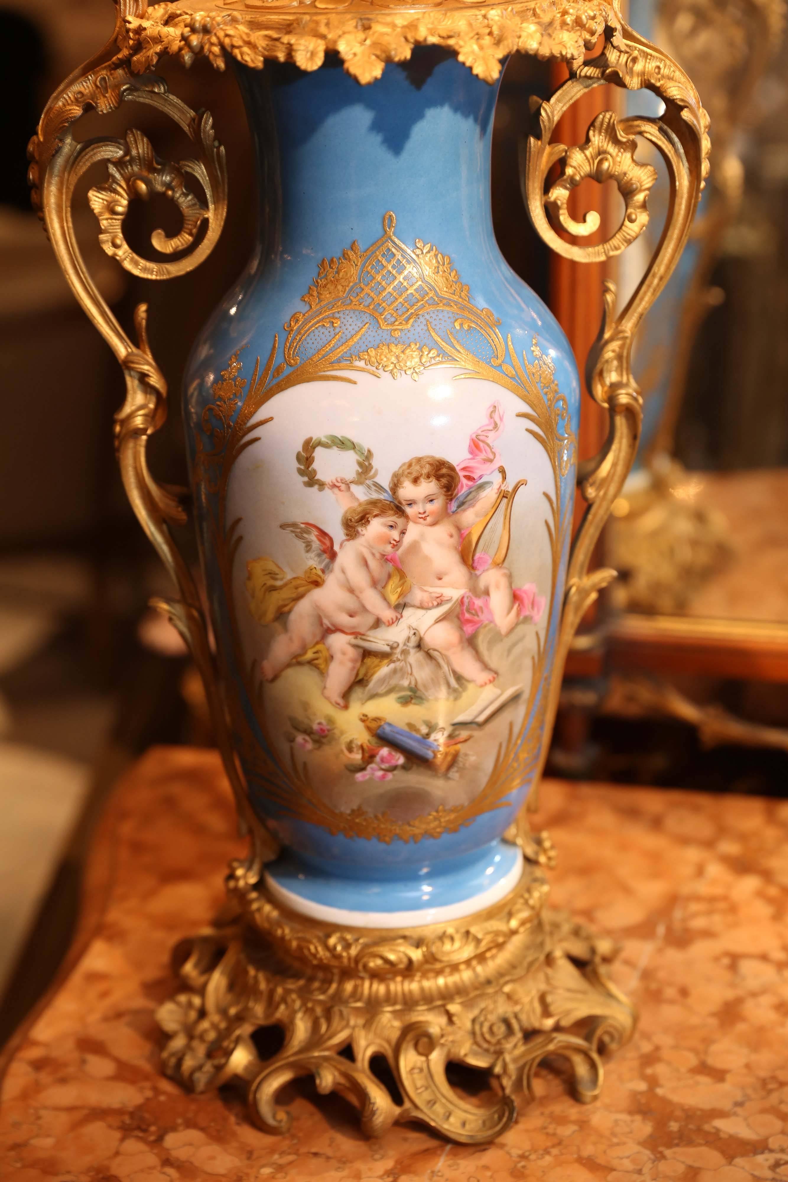 Bronze doré mounts decorate this Sèvres lamp with scrolling arms on each
side. The Sèvres Porcelain is painted with playful angels on one side and
a floral motif on the verso. Bronze gilt base.