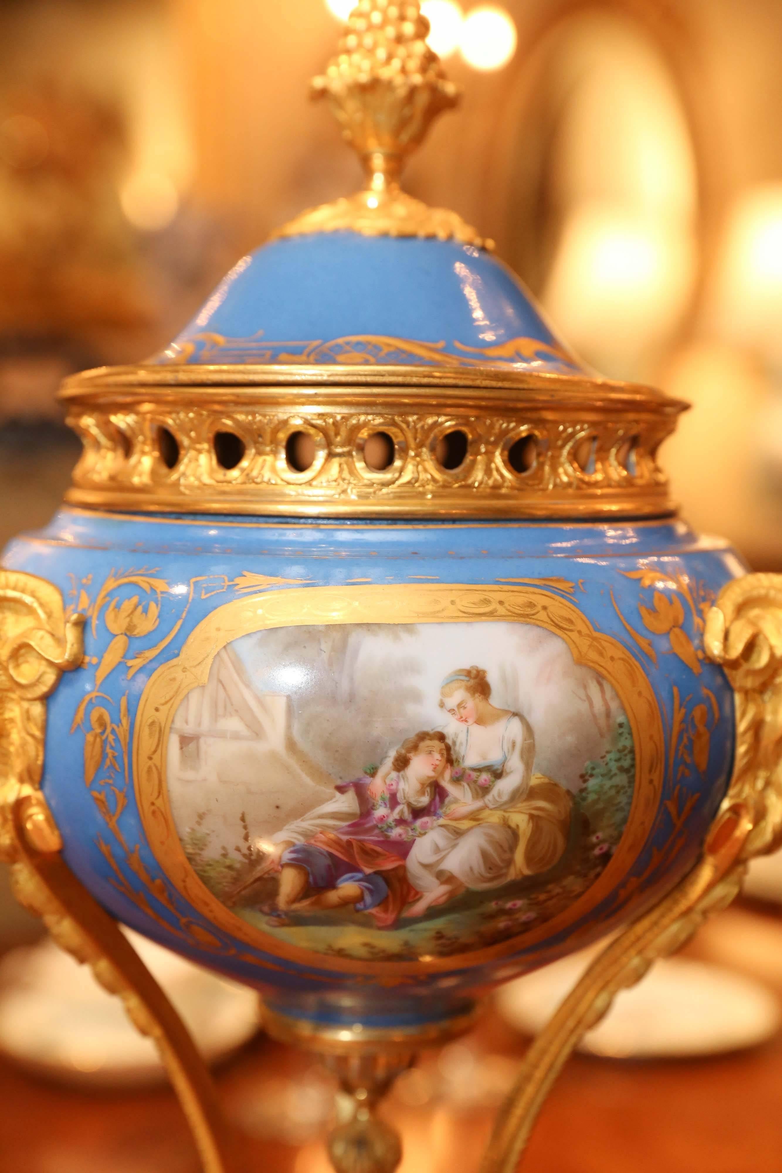 Exquisite Sèvres porcelain parfoams in celeste blue. Bronze doré mounts
that support a bowl shaped urn ending in a acorn shaped finial. 
The porcelain has reserves painted on three sides of a courting couple in a garden settings. The bronze mounts