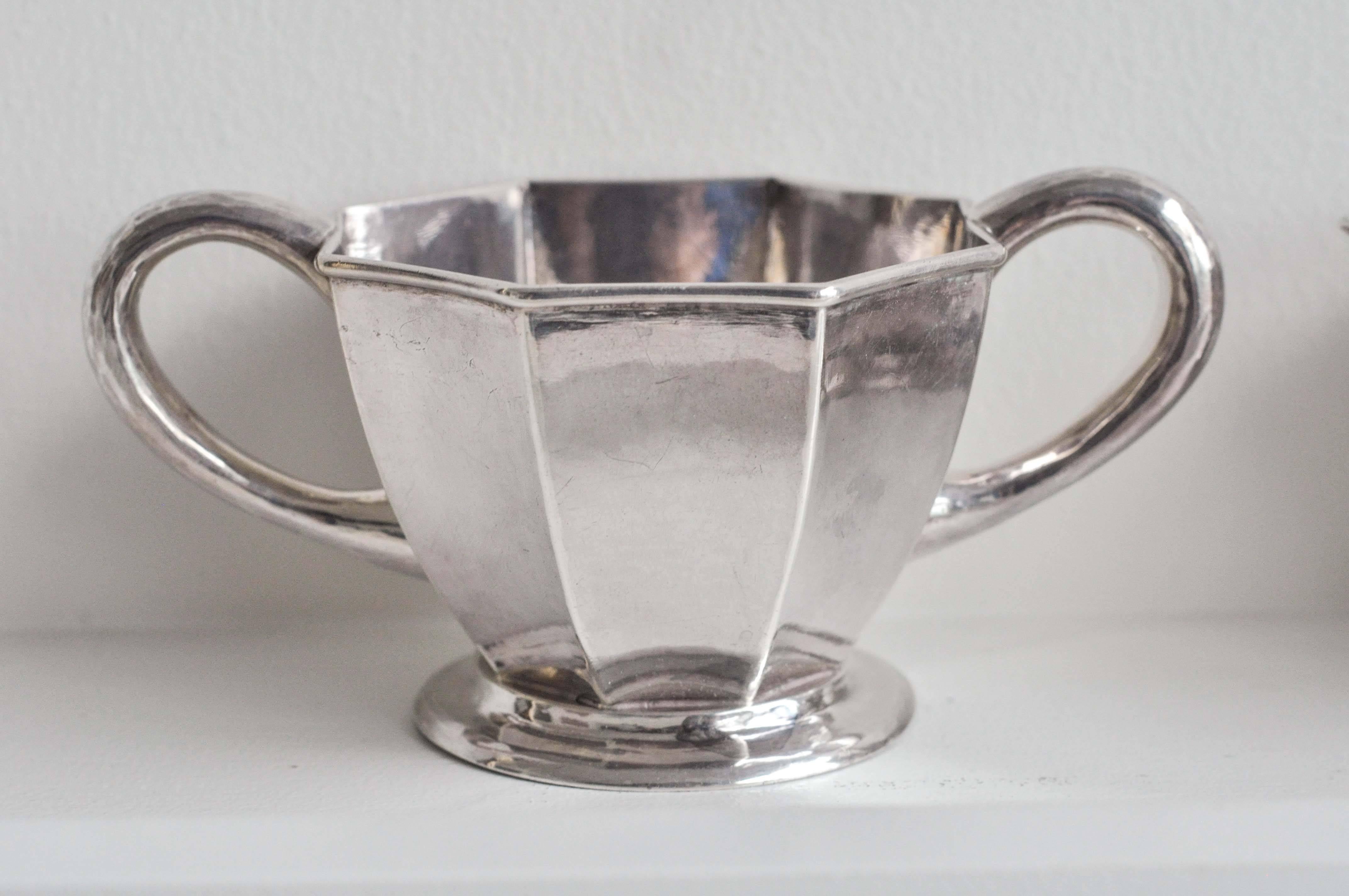 An elegant sterling silver sugar and creamer set by The Kalo Shop, Chicago, from the Arts and Crafts/ Art Deco period, 1914-1918. Beautifully hand-hammered, heavy guage sterling silver and an elegant faceted design. Marked:
