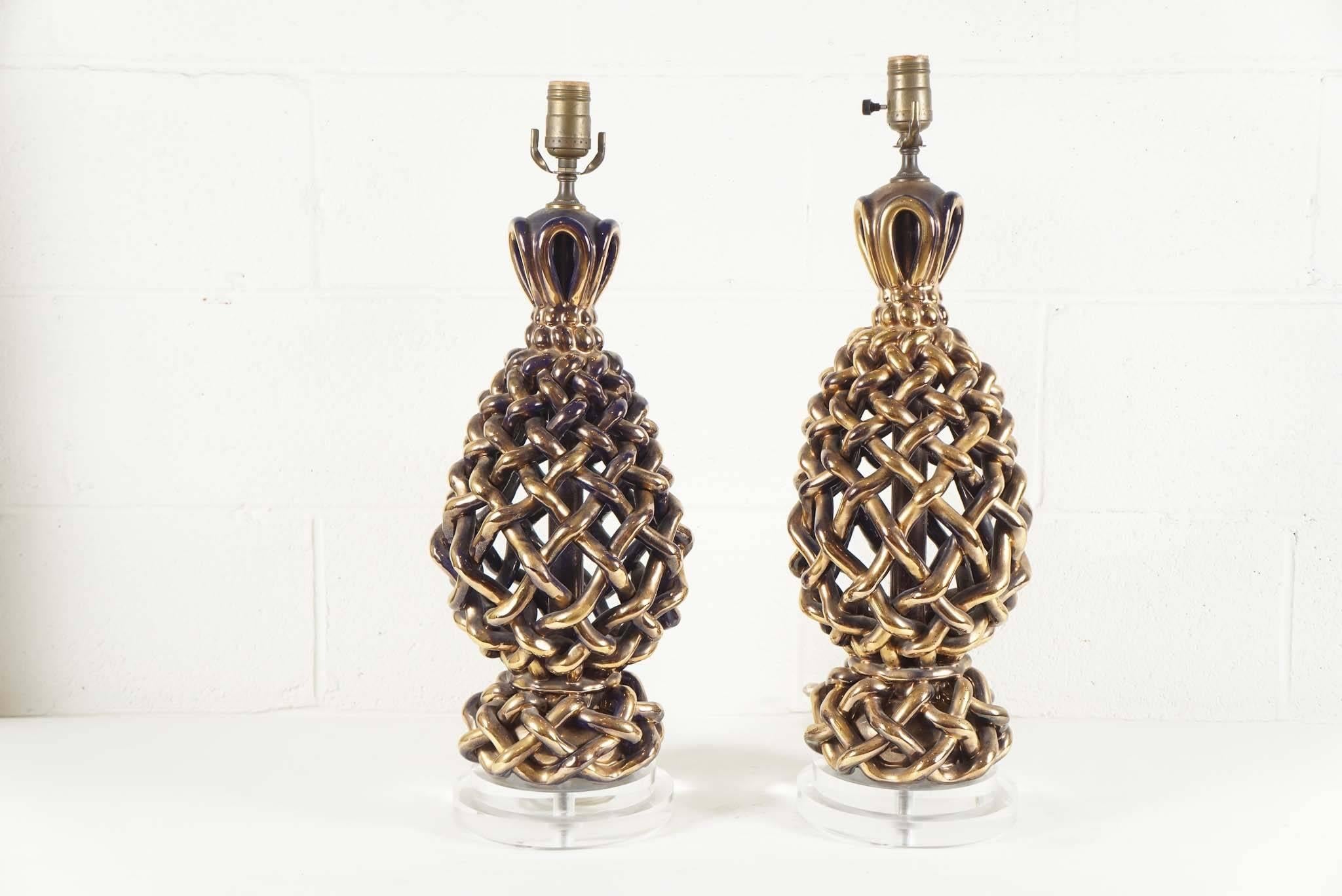 Here is an amazing pair of Italian ceramic lattice woven lamps.
The finish on the lamps is a metallic golden bronze with a hint of black.
The lamps are mounted on an inset double Lucite round base.