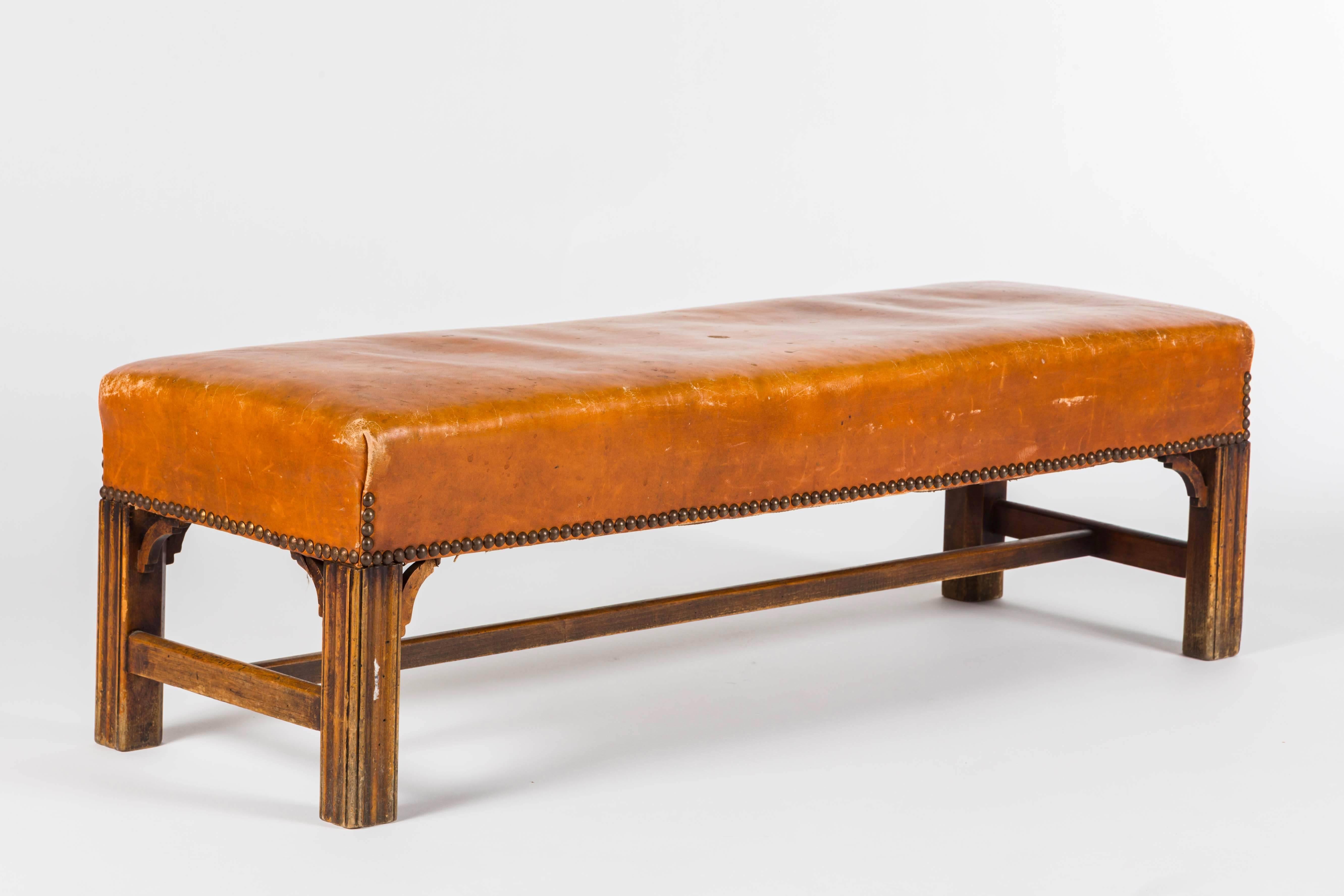 1930s English mahogany low bench with original leather top and brass nailhead detail.
