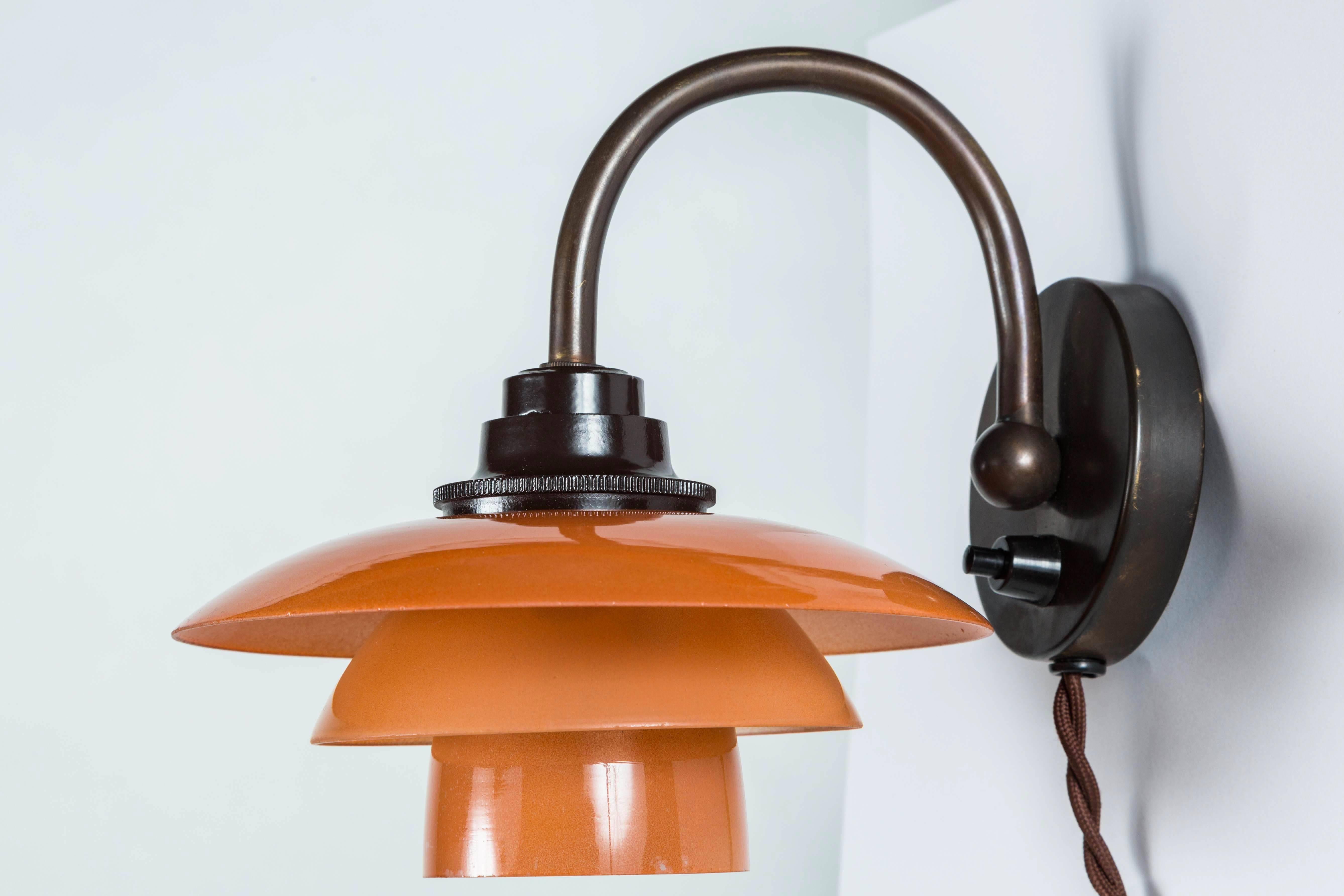 Downward wall lamp by Poul Henningsen. Model PH-1. Curved browned brass arm with salmon colored matte glass shade. Bakelite socket cover. Denmark, circa 1933. 
 