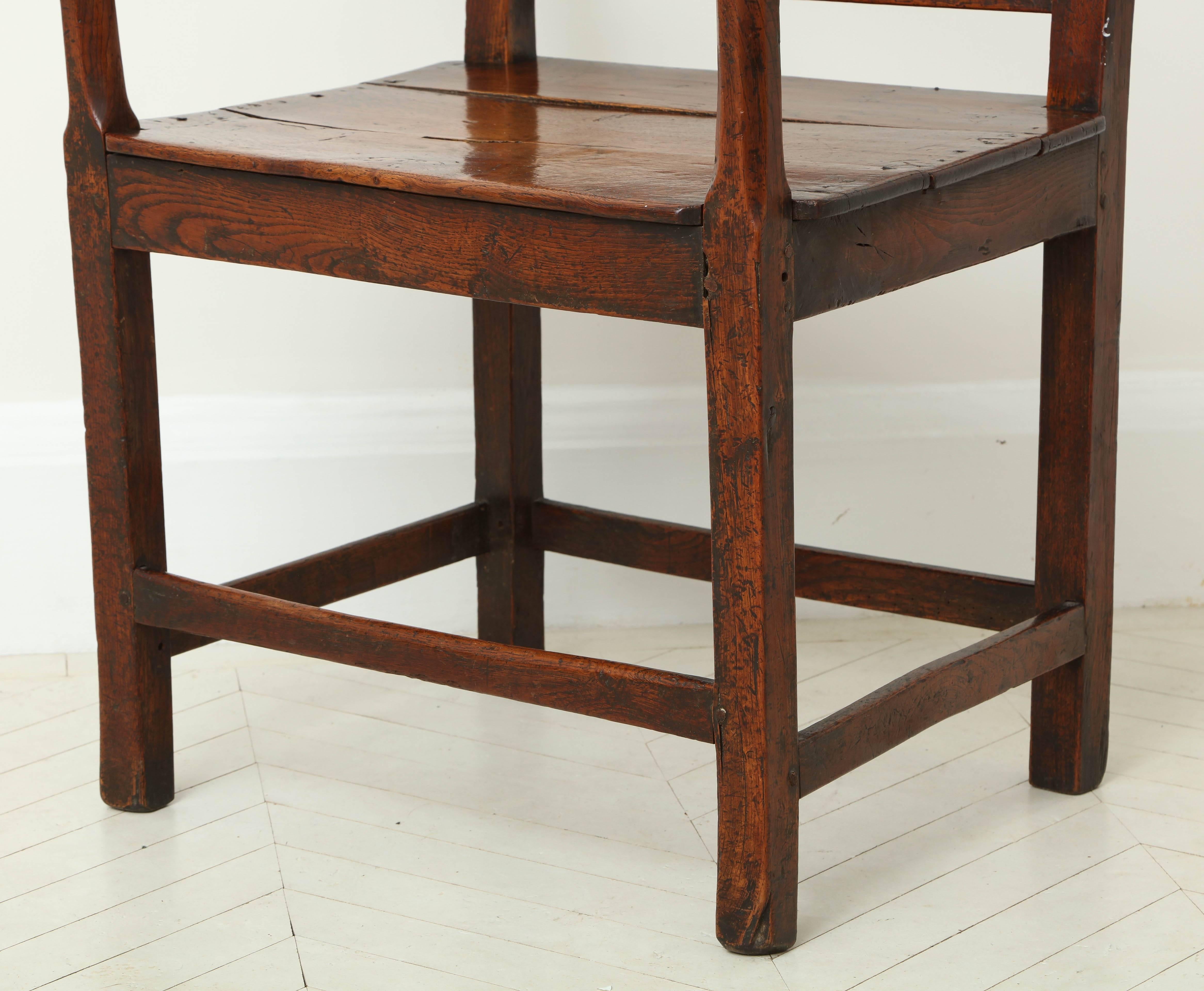A George III stained oak armchair with solid seat.