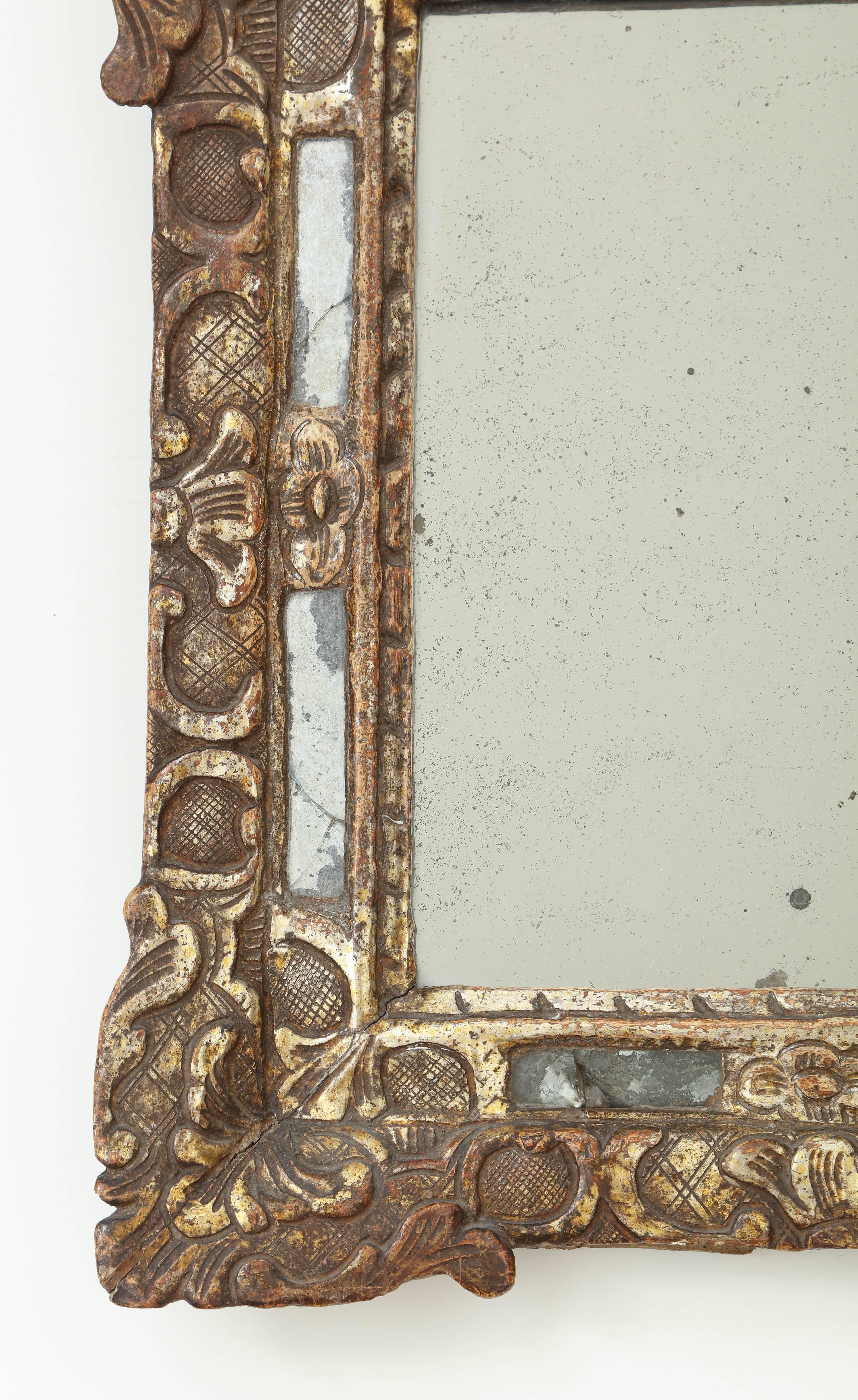 An 18th century French Regence carved and gilded mirror with original silvered glass and slip glass border.