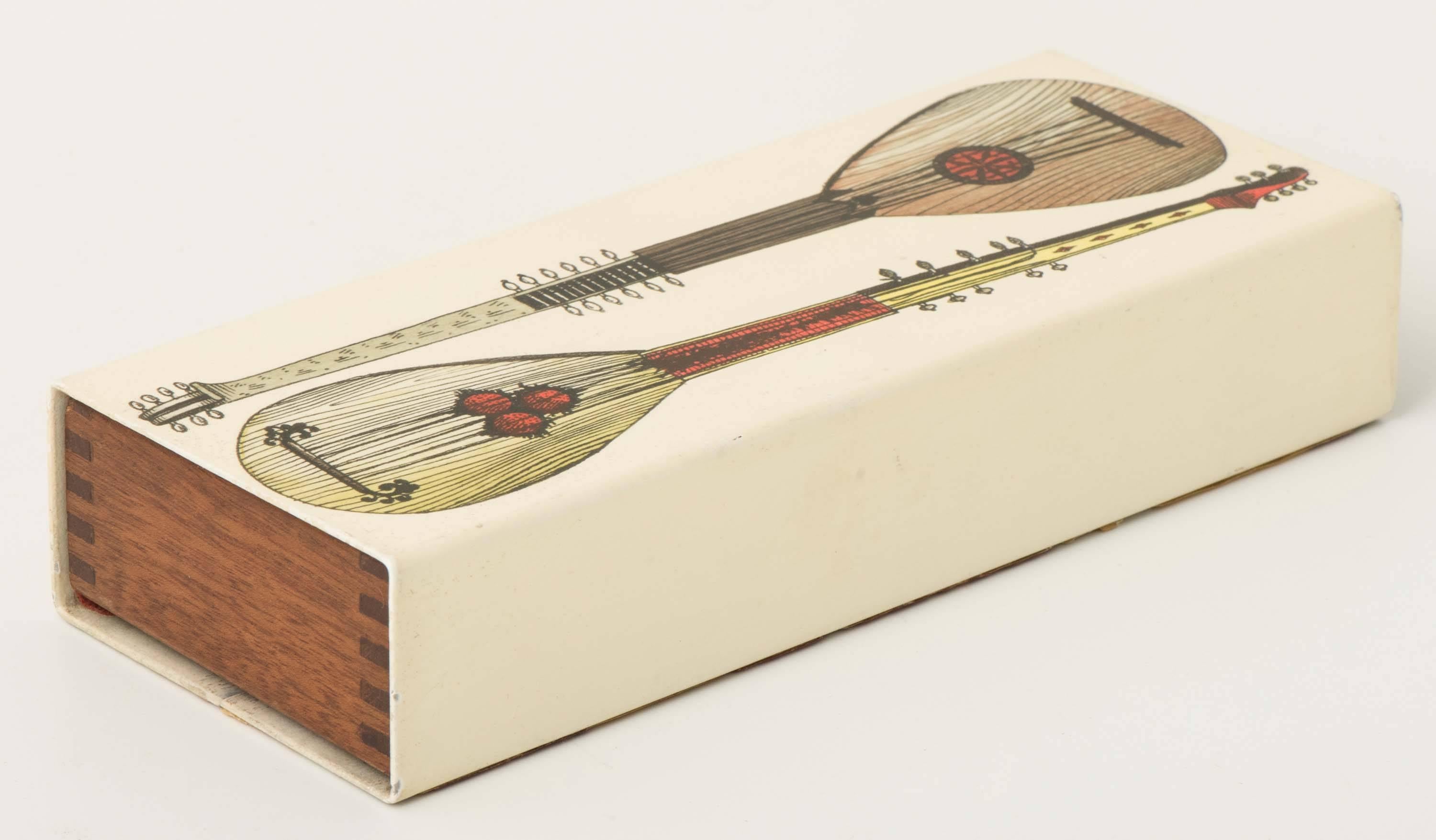 A Piero Fornasetti box,
“Strumenti Musicali.”
Metal lithographically printed and hand-colored. Mahogany,
Italy, circa 1950.
Measures: 4 cm x 20.2 cm x 8 cm.
 