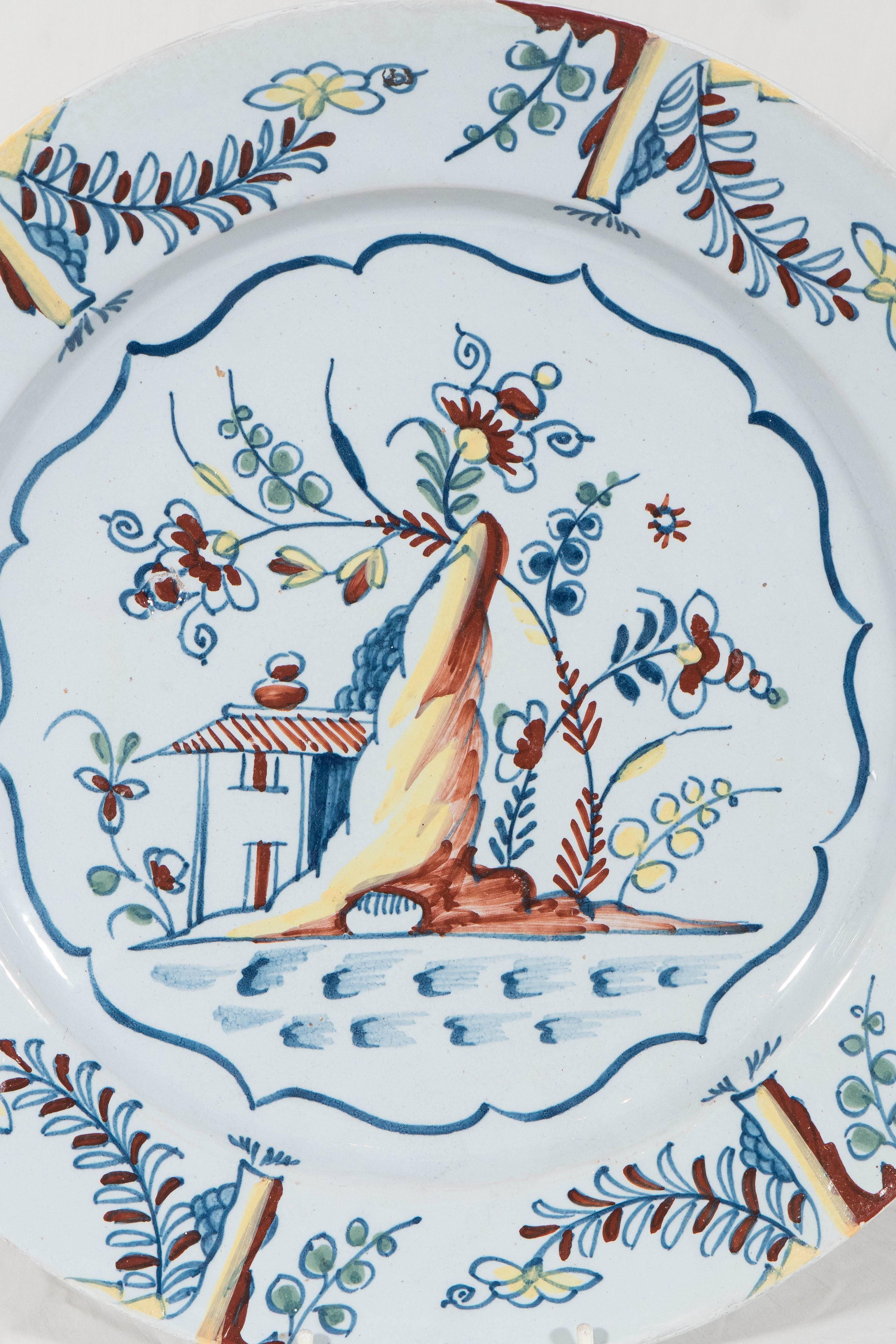 We are pleased to offer this lovely mid-18th century Bristol Delft charger with the well painted vibrant scene. We see a traditional country home, a flowering tree, and a rocky outcropping. The scene features  the polychrome colors in use at