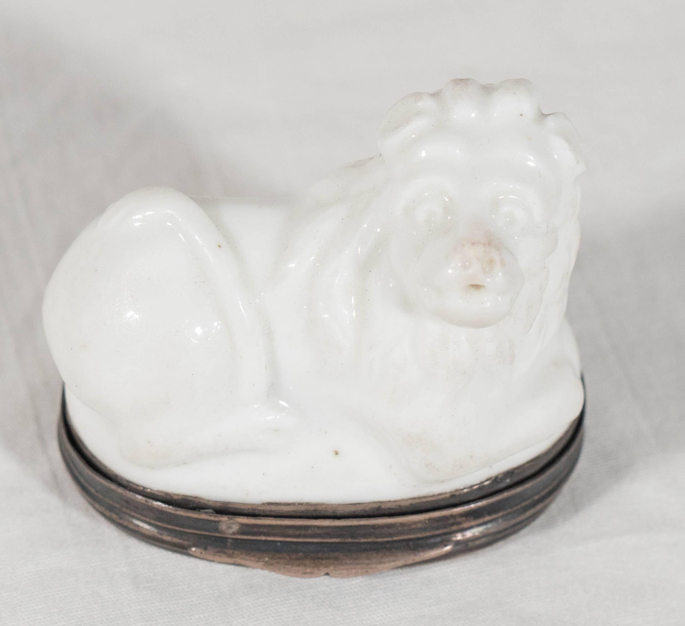 A rare mid-18th century porcelain snuff box naturalistically modeled as a lion. The silver mount with the decharge of Eloy Brichard, Paris. The lion recumbent with his tail wrapped over his back. The base is decorated with a single flower. (There is