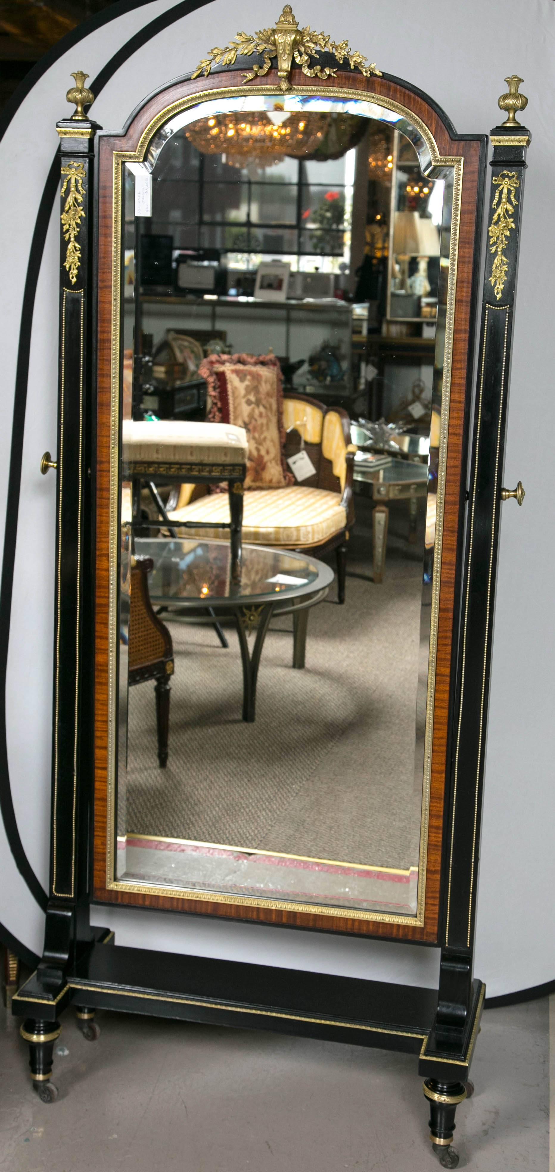 Bronze-mounted cheval tilting mirror by Maison Jansen. This mirror is simply a work of art in and of itself. The finest bronze castings seeming like jewelry quality run up and down this wonderfully ebony mirror frame with rosewood banding. The whole