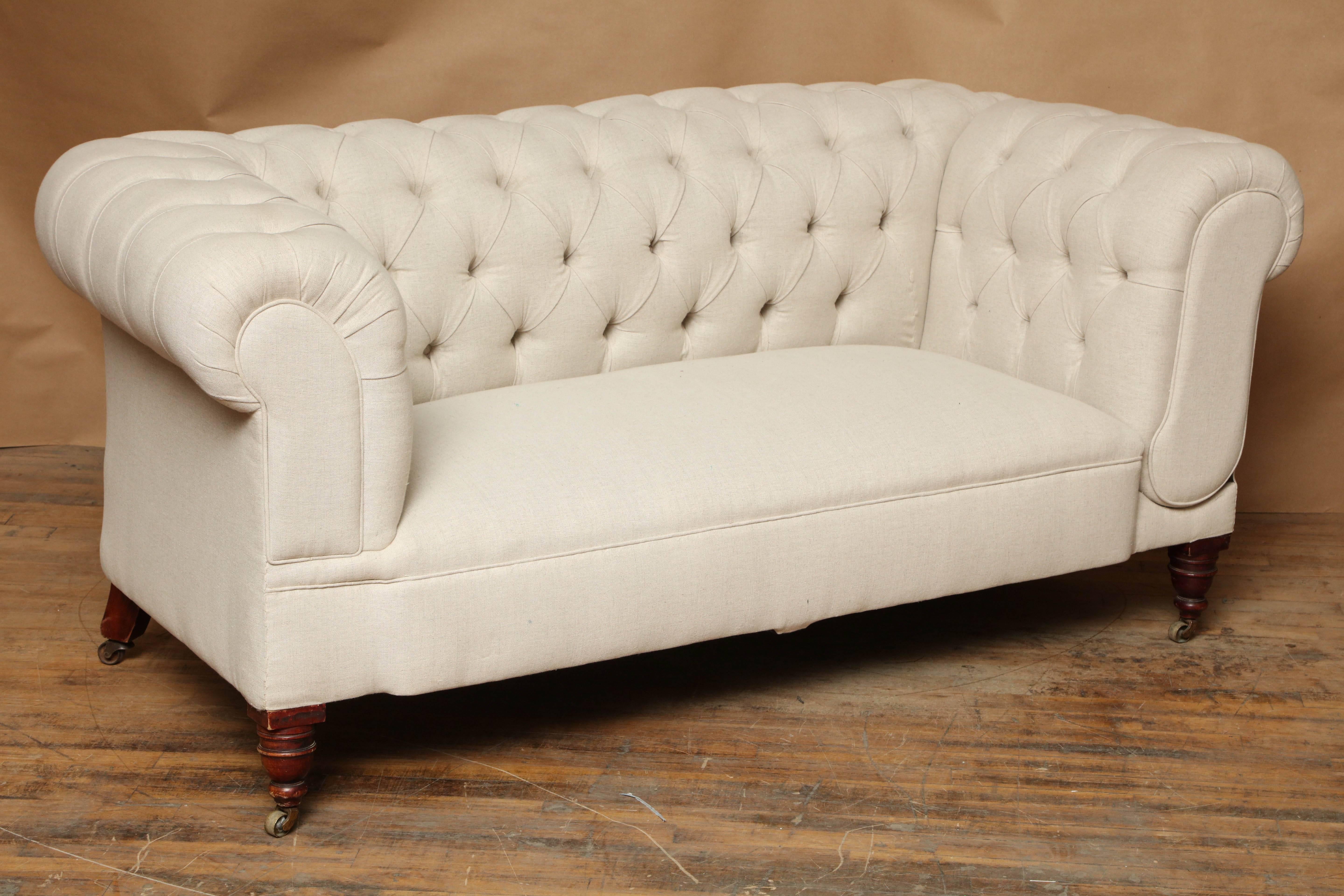 English Chesterfield sofa has been reupholstered in natural colored linen fabric. Diamond tufting on inside and top of backrest and inside of rolled arms. One arm has a hinge release lever on the side that lowers the arm and allows the sofa to be