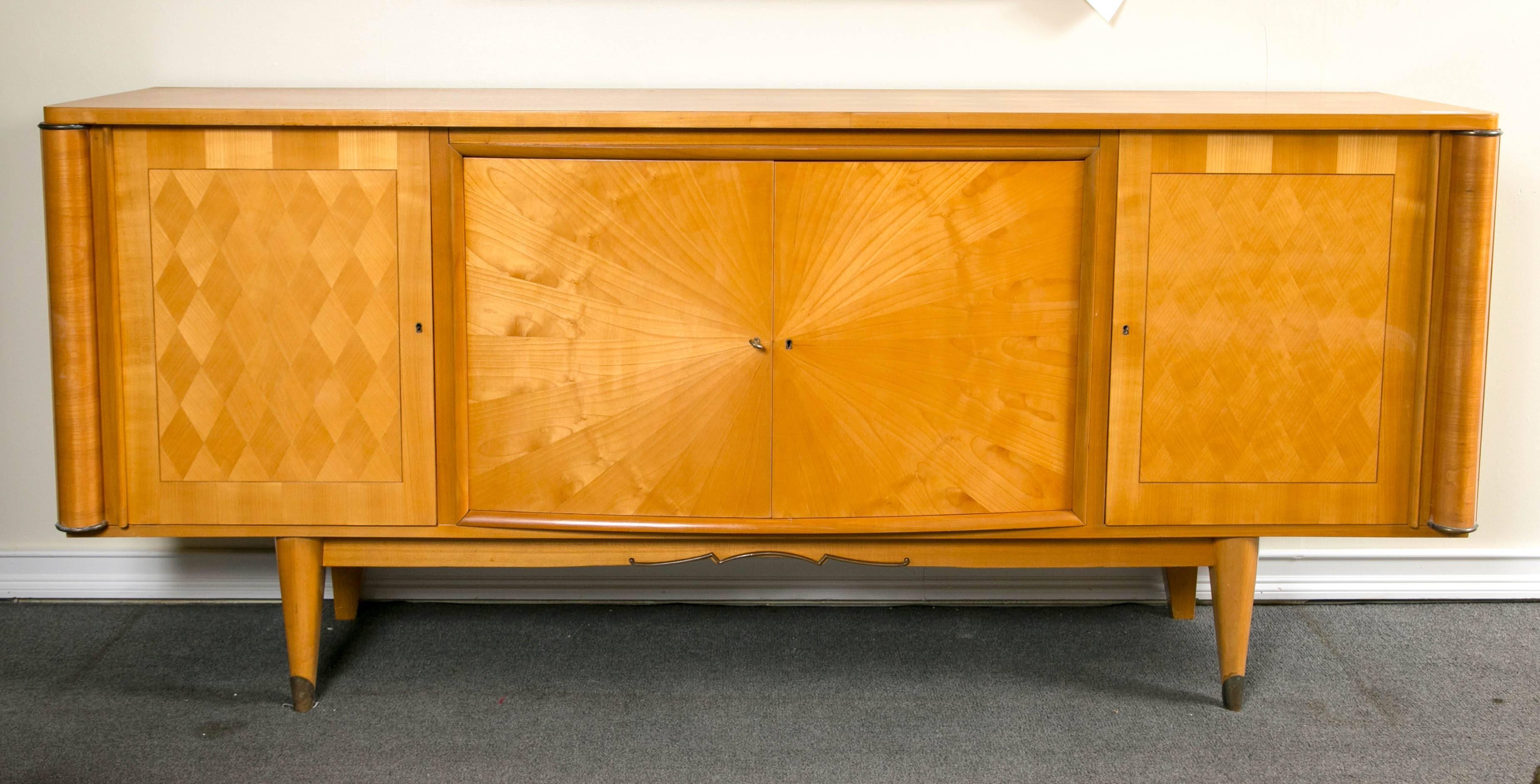 French palatial blonde mahogany sunburst inlaid sideboard. A blonde mahogany French four-door sideboard having starburst form grain on the center doors flanked by diamond form grain doors, circa 1950s. This extraordinary sideboard is exquisite in