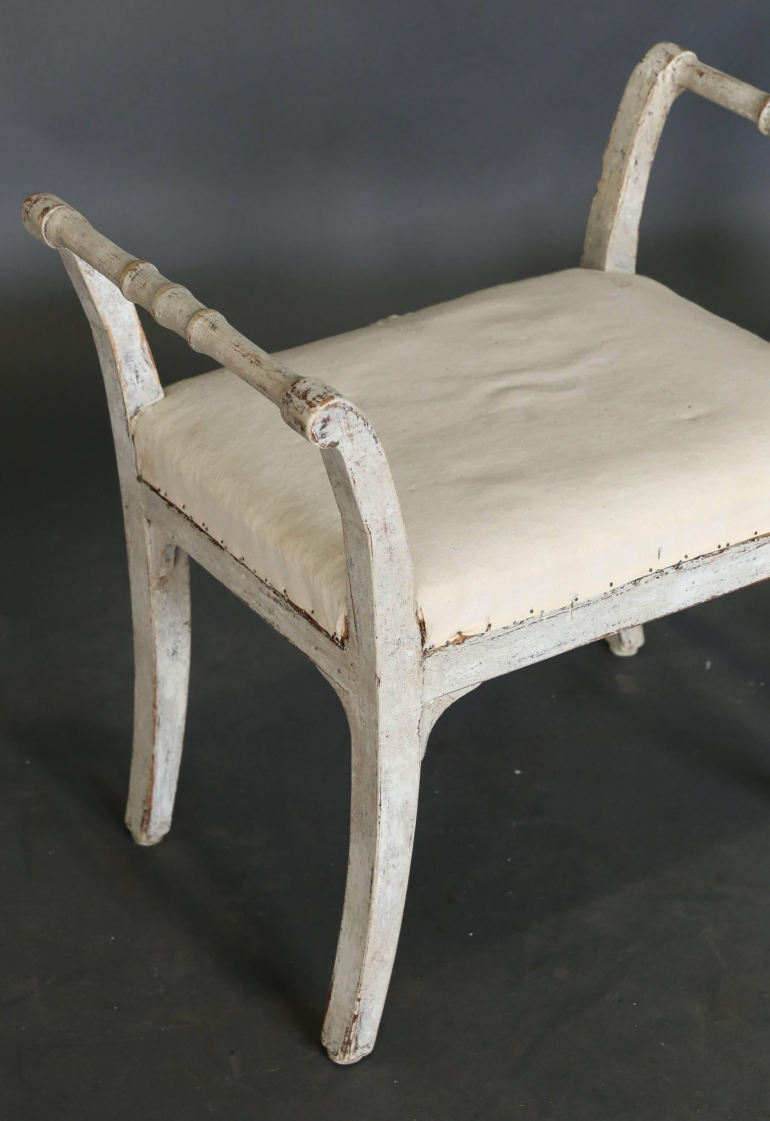 Pair of 19th century upholstered Swedish Benches or Stools with slightly saber legs and rounded detail on the arms.