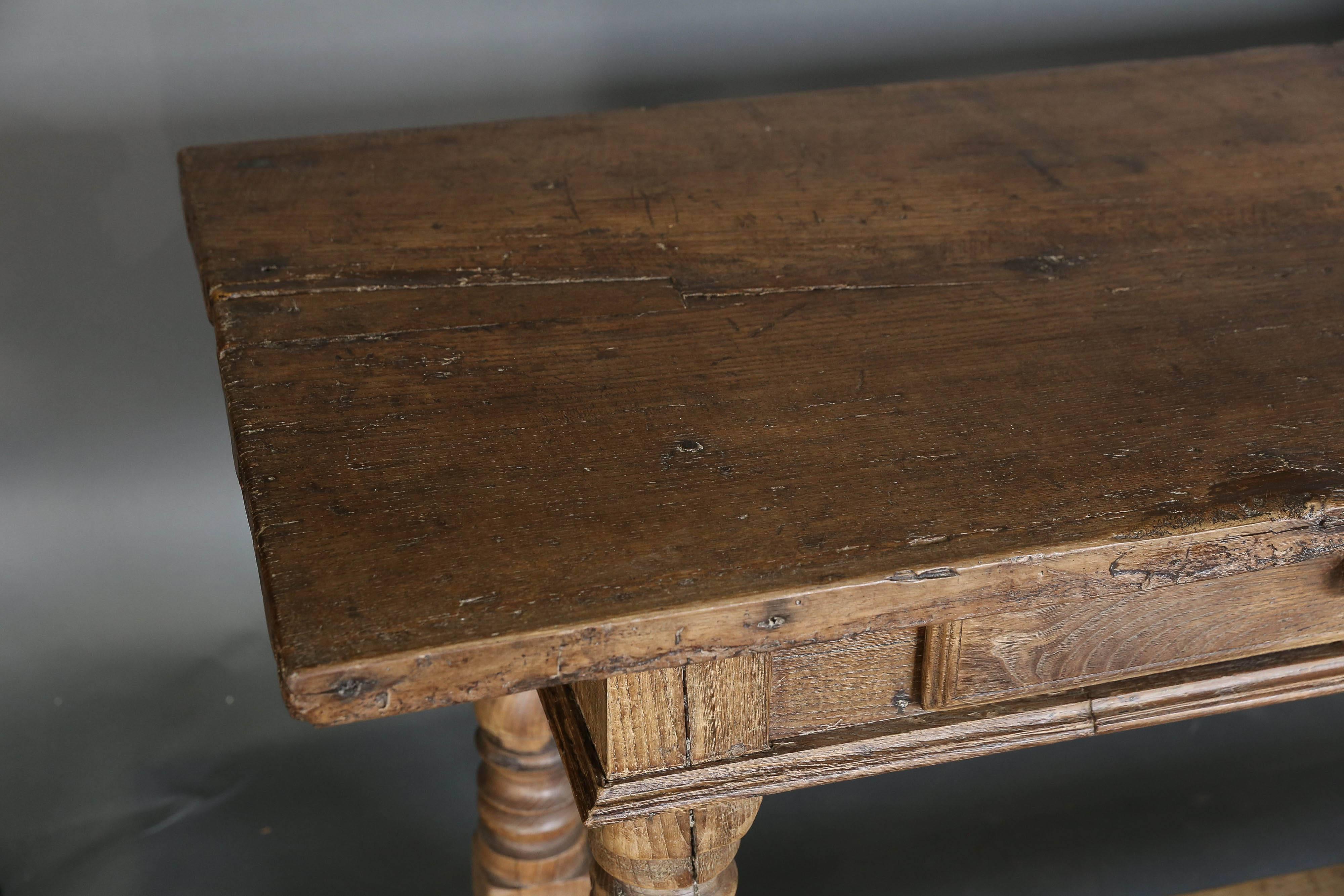 19th century Spanish chestnut table with a pair of drawers and wooden knobs. The top is a single plank.