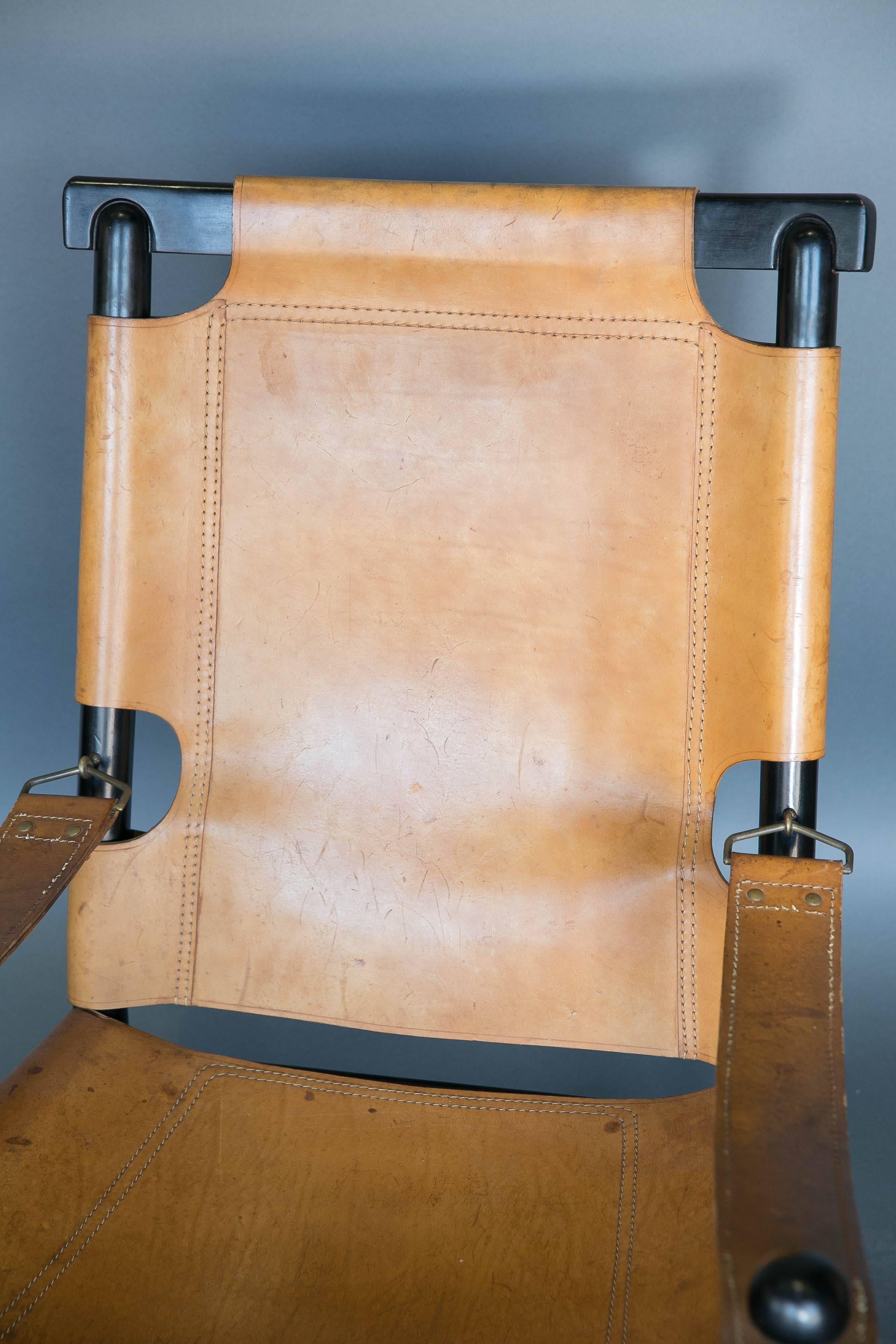 Vintage leather and ebonized wood chair from the 1960s. Arm straps are connected with metal fittings. Leather has rich patina.
