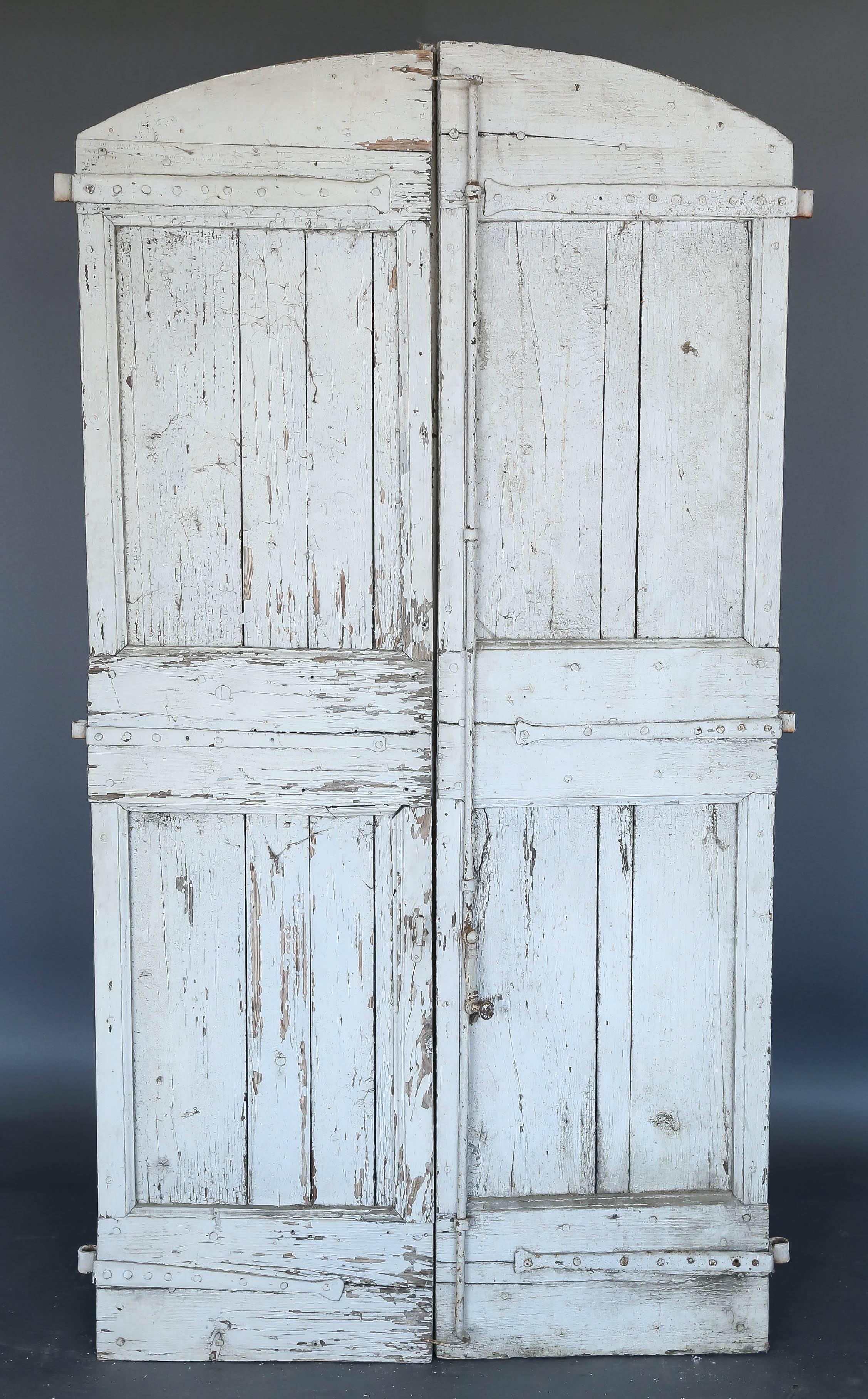 Pair of 18th century. French eyebrow shape shutters with original hardware scraped white paint. Wonderful weathered patina. The weathered look is from years of exposure to the elements. The shutters are sturdy. They would make wonderful doors.