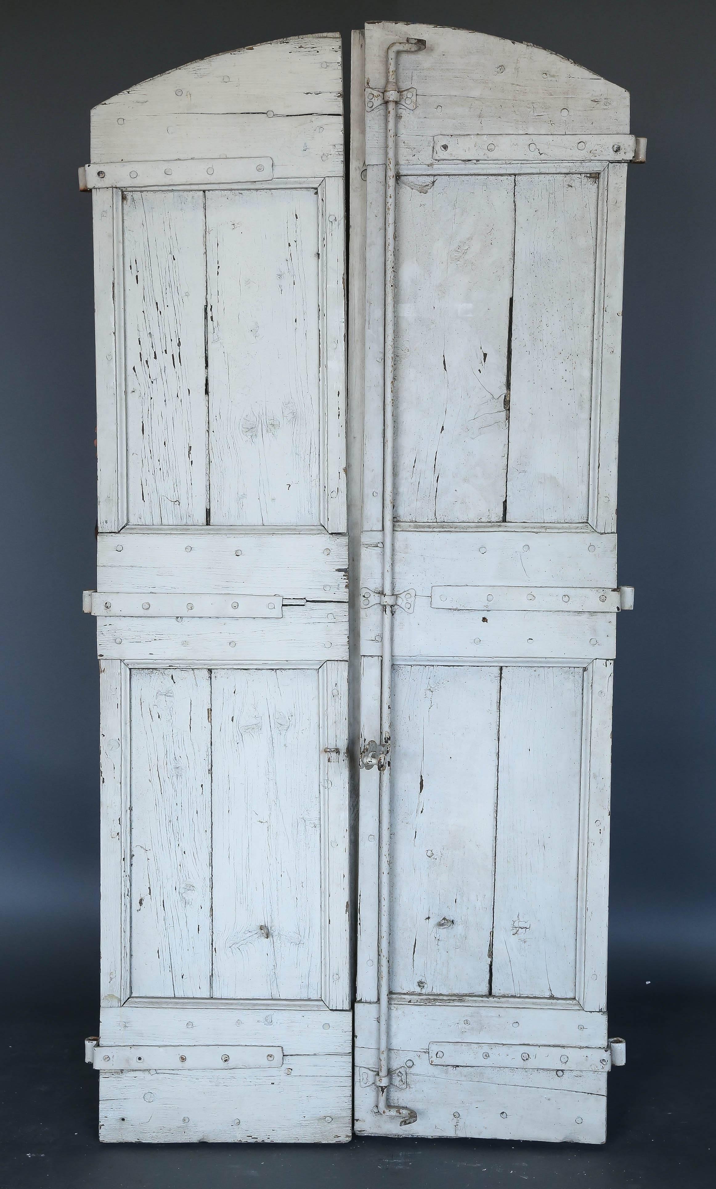 Pair of 18th century French eyebrow shape shutters with original hardware scraped white paint. Wonderful weathered patina. The weathered look is from years of exposure to the elements. The shutters are sturdy. They would make wonderful doors.