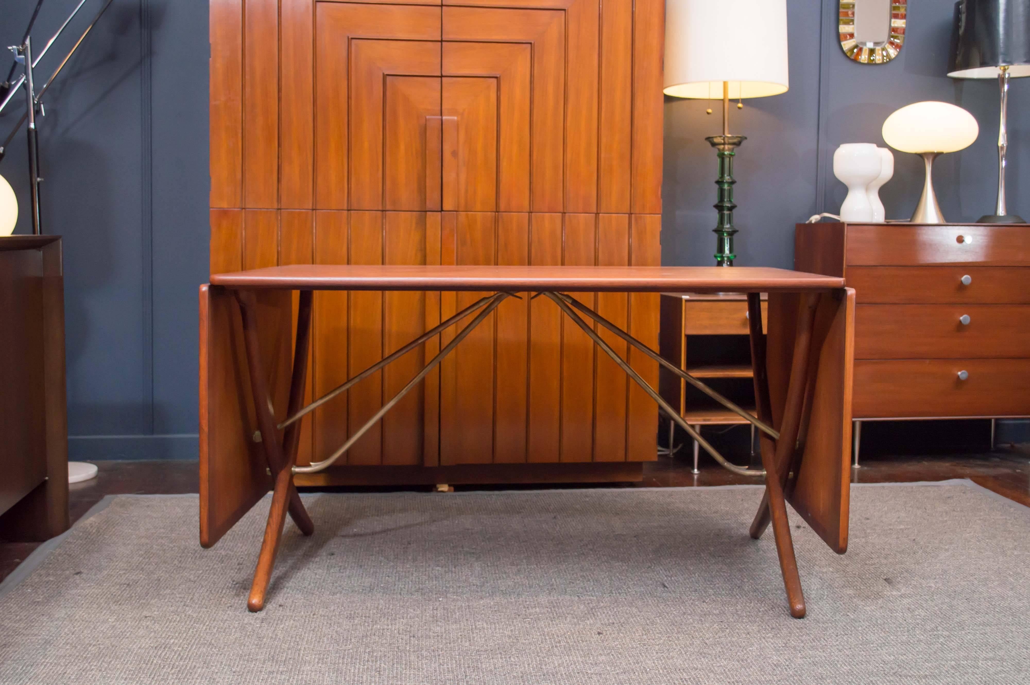 Rare Hans Wegner design teak drop-leaf dining table produced by Andreas Tuck, Denmark. Perfectly refinished teak table top on oak sabre legs with brass supports. Labeled and stamped.