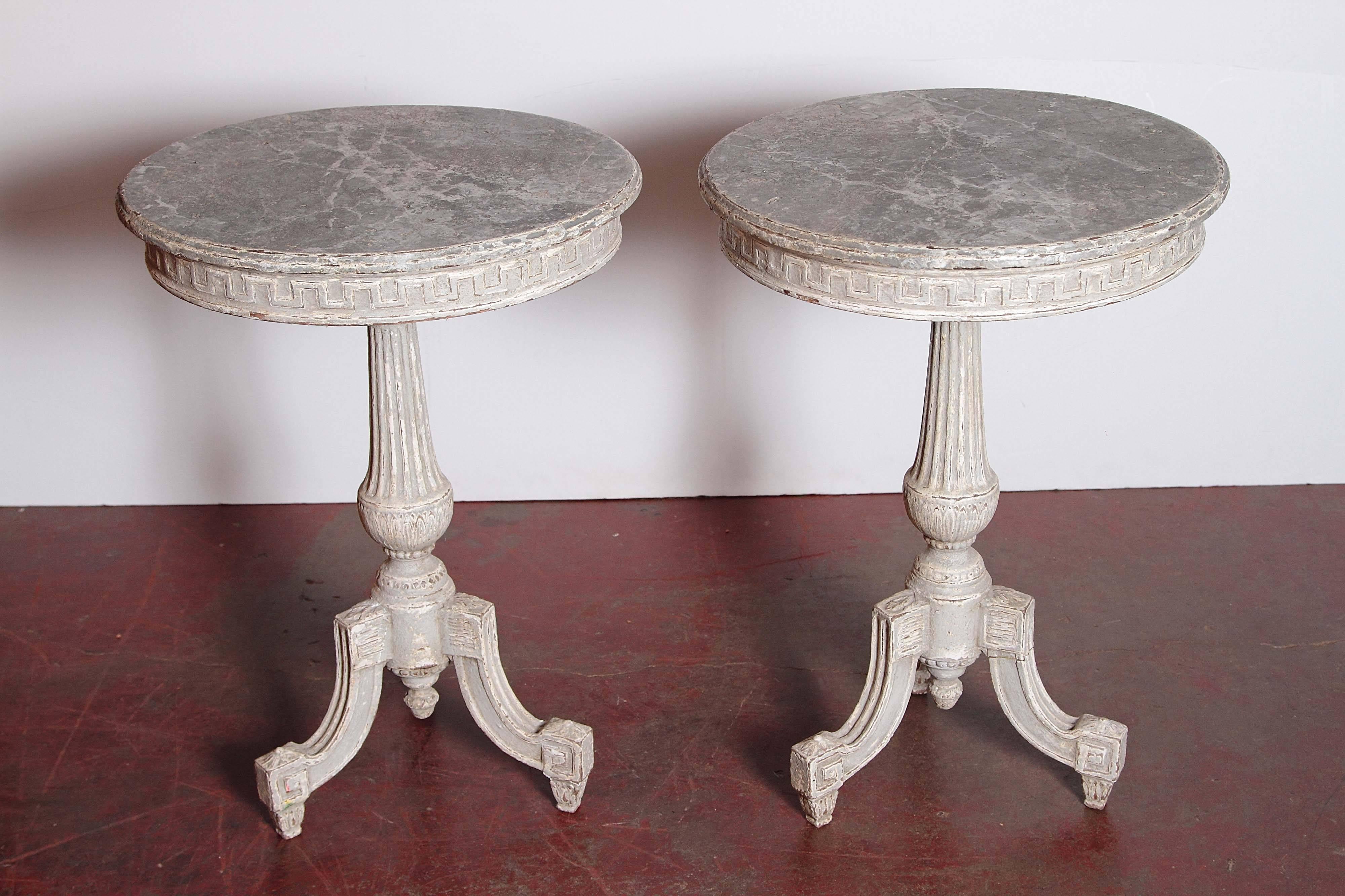 This elegant pair of antique side tables was crafted in Paris, France, circa 1880. Round in shape, each pedestal has a tapered, fluted stem, three legs and features a nicely carved apron with a Classic Greek key motif. Both tables are painted grey