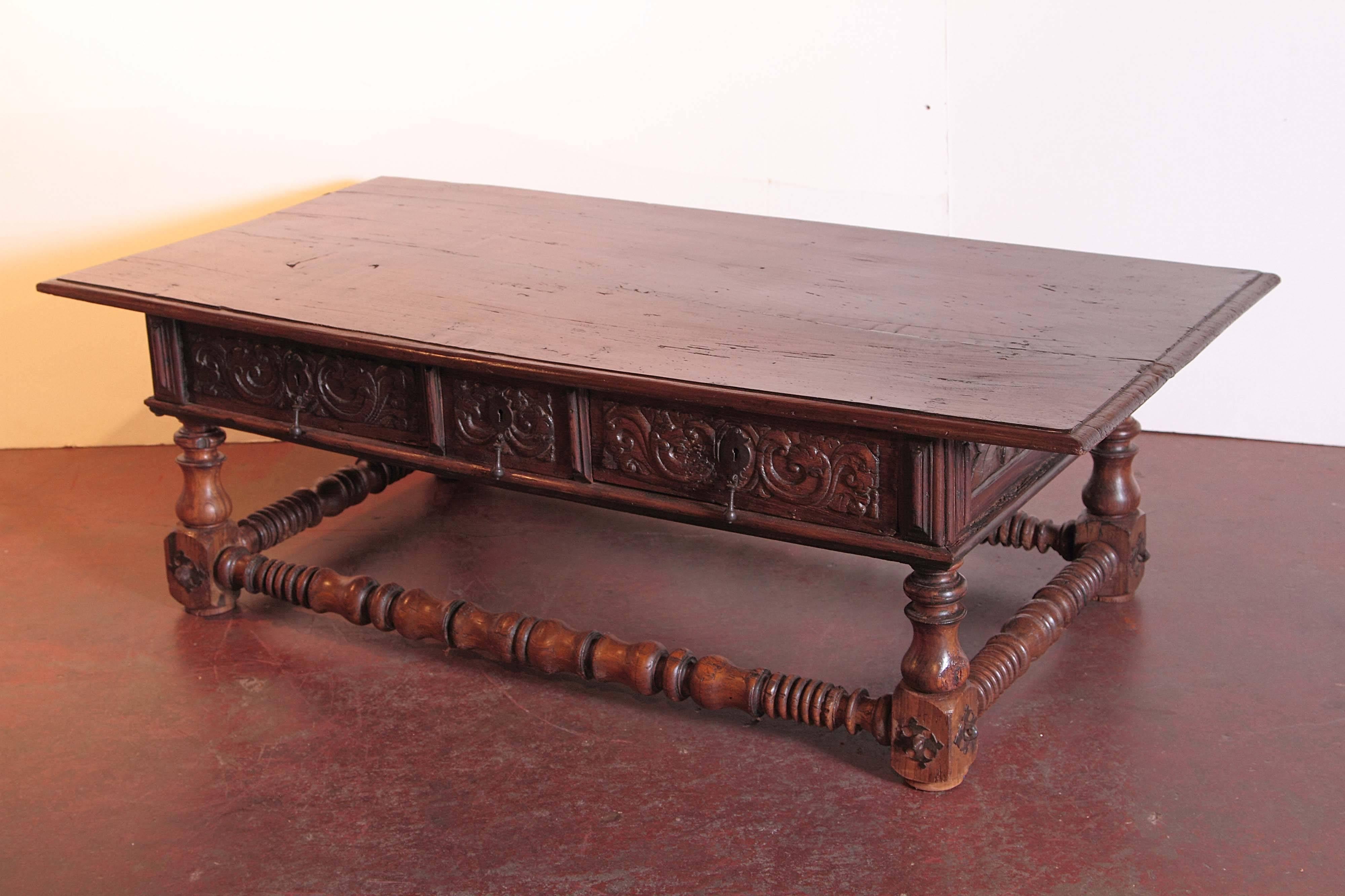 Make a beautiful statement in your living room with this elegant fruitwood coffee table from Spain. Crafted, circa 1780, the antique table is hand-carved on all four sides including the three drawers across the front with their original wrought iron