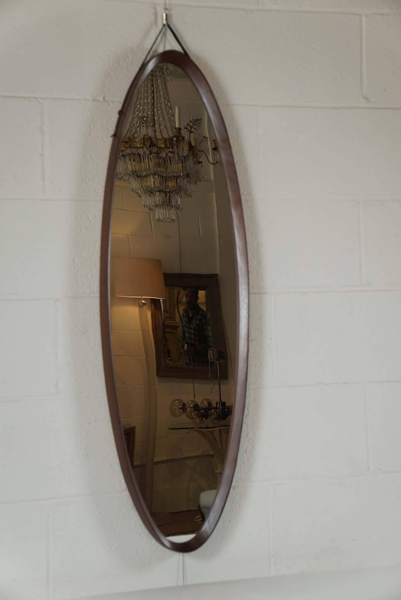Here is a narrow oval mirror with an inset frame in walnut.
The mirror has a vintage leather strap for hanging.